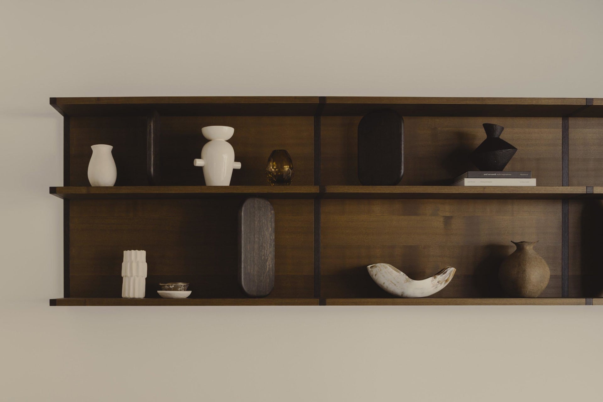 Minimalistic wooden floating shelves with assorted decorative items on two shelves against a plain wall.