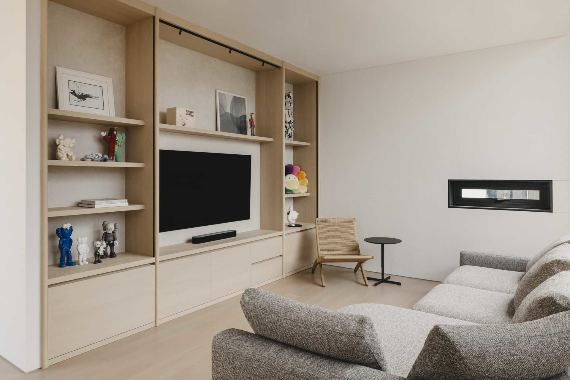 Contemporary living room with minimalist design, featuring a grey fabric sofa, wooden shelves, and a modern fireplace.