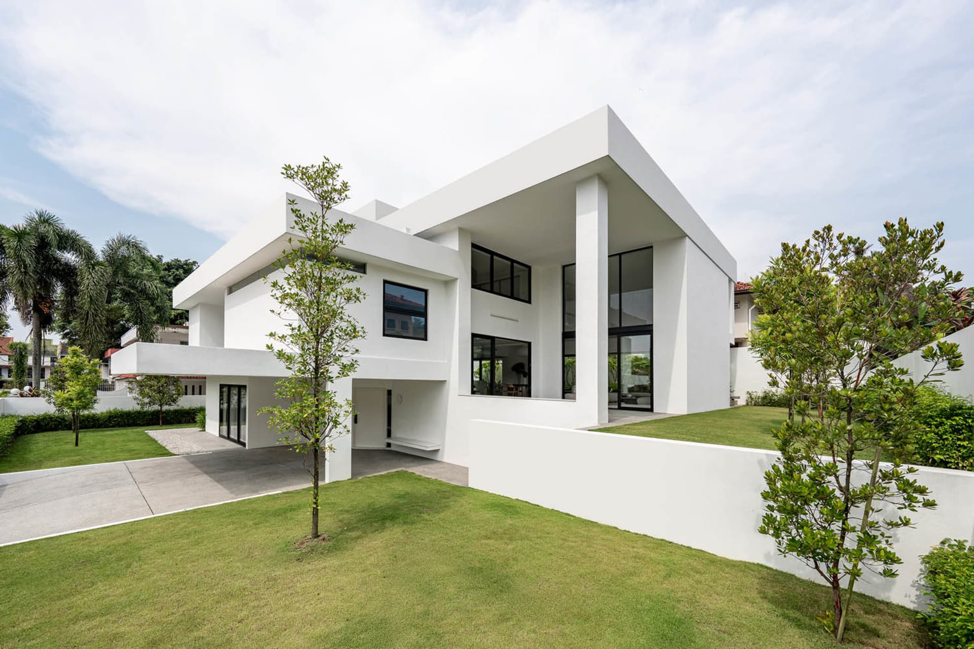 Modern minimalist house with white concrete exterior and large windows.