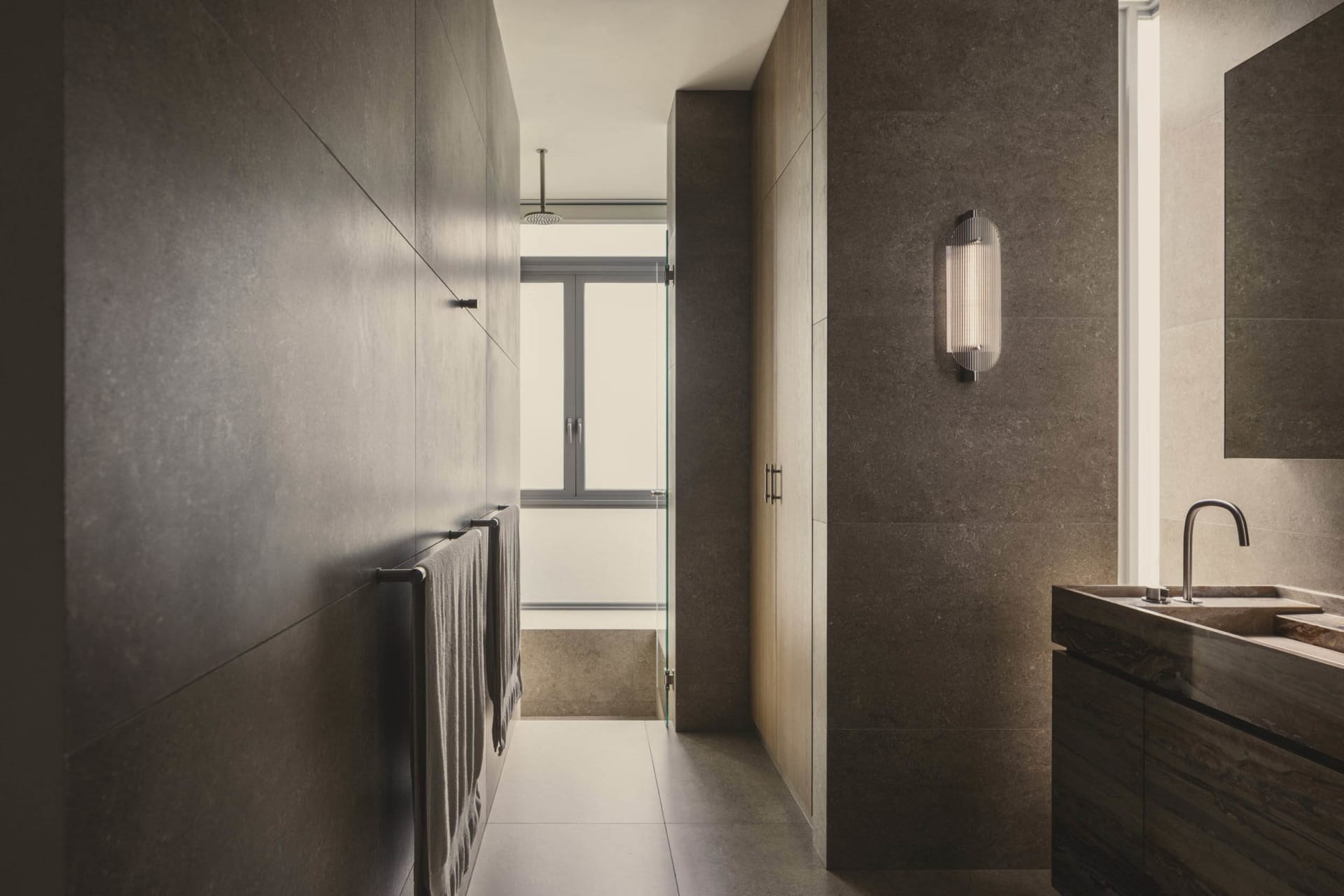 Modern bathroom with concrete walls and floor, featuring a sleek, minimalist design with a light fixture, window, and sink.