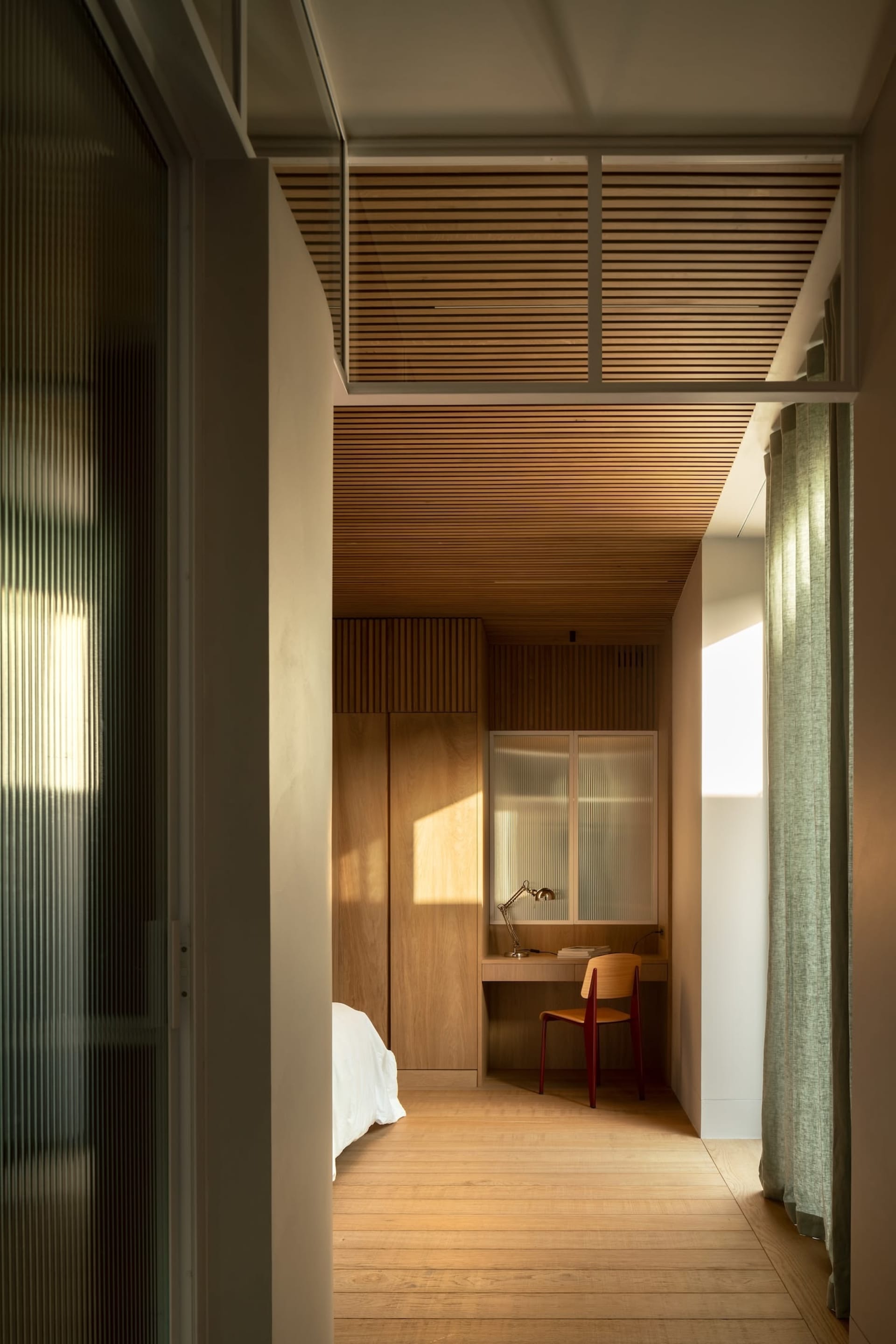 A modern bedroom with wooden furniture and a small workspace area.
