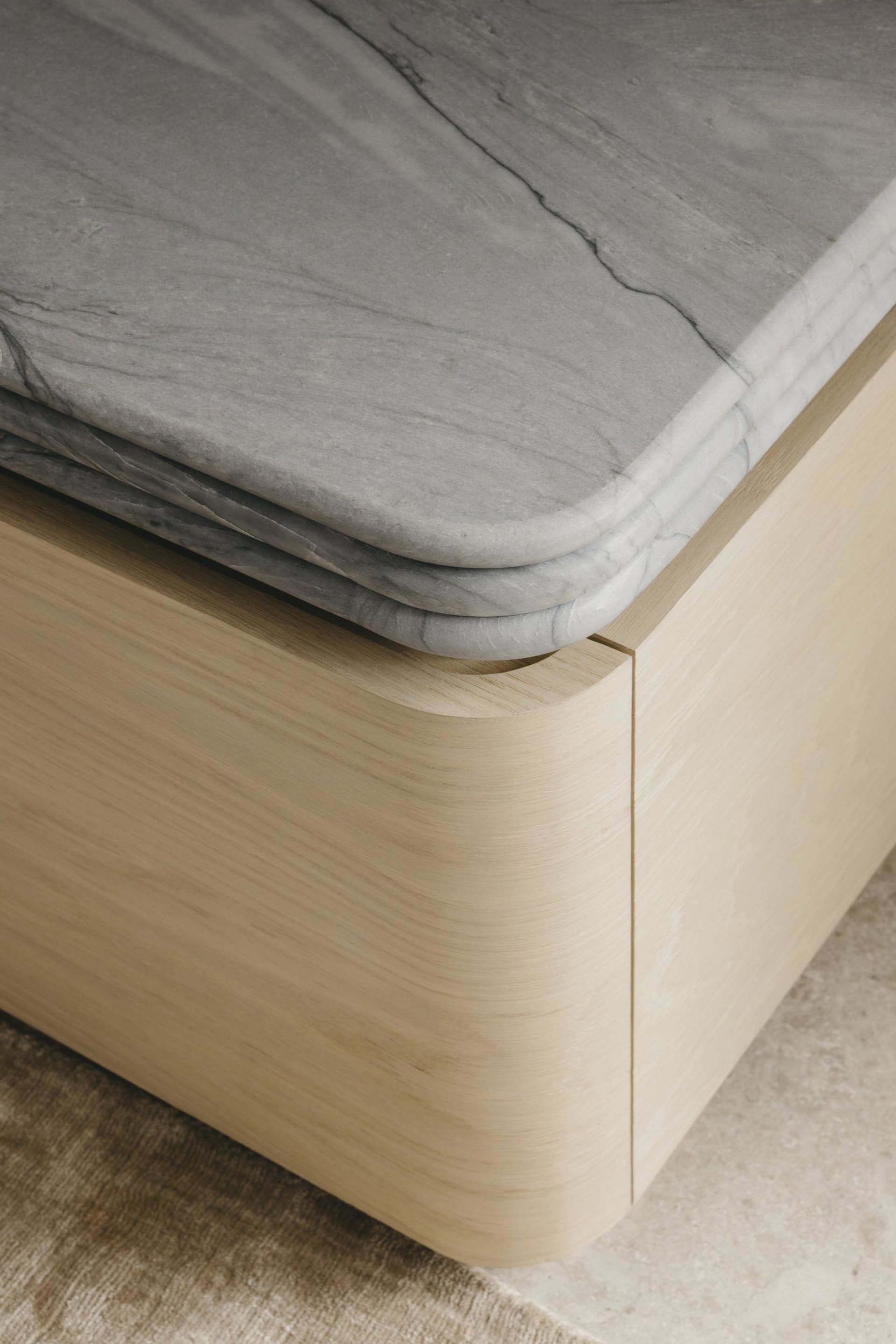 A modern interior space featuring a wooden bench with a marble top on a plush rug.