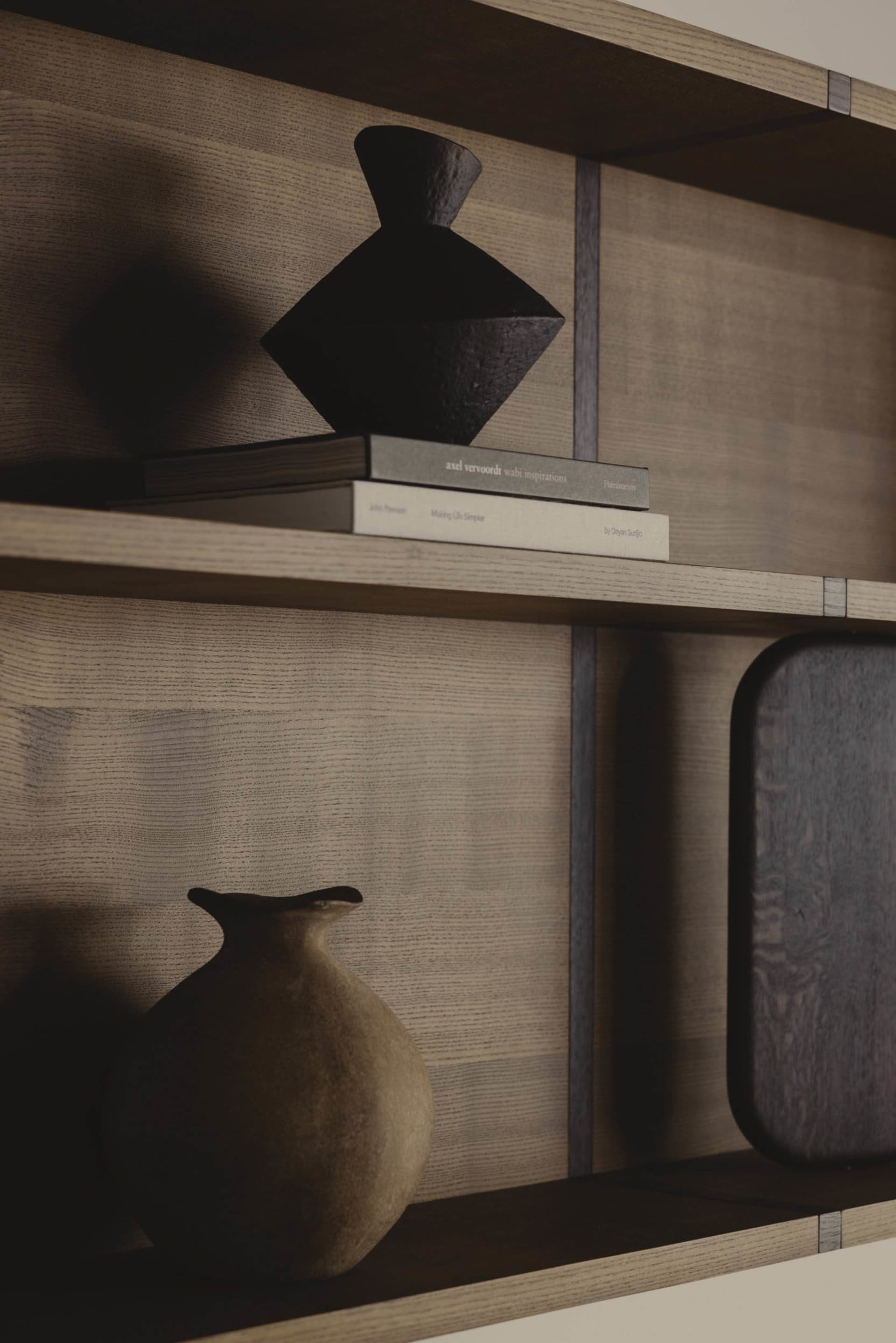 A modern wooden shelving unit displaying books, vases, and decorative objects.