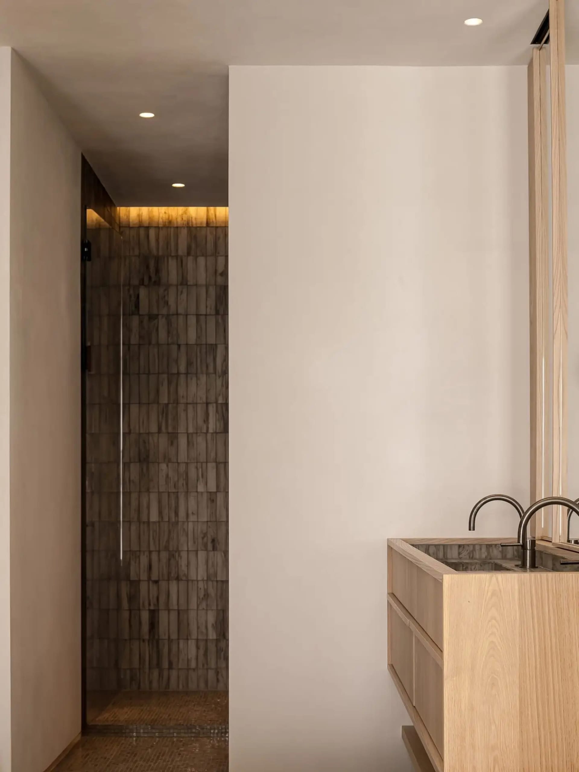 Minimalist bathroom with wood vanity and stone walls.