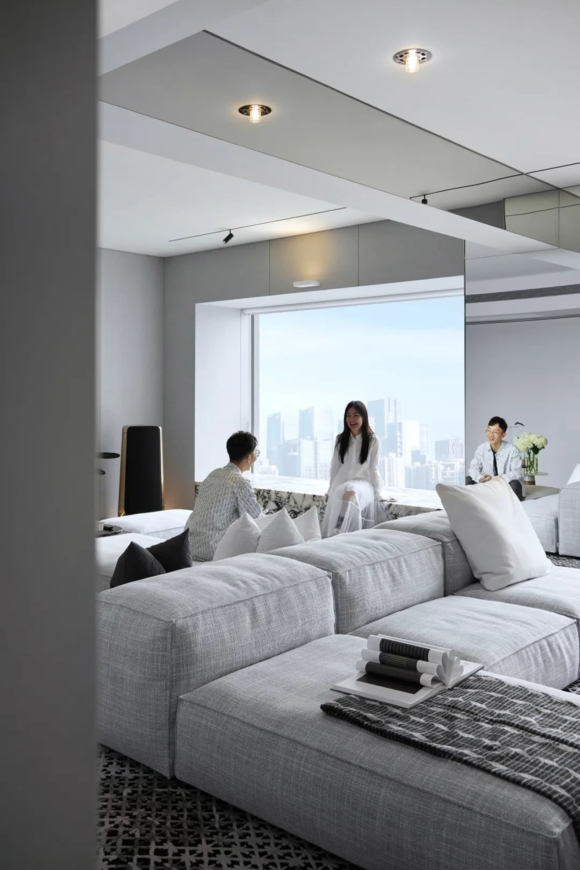 現代客廳內有布面沙發、大理石地板,以及可俯瞰城市景觀的雙層挑高窗戶。