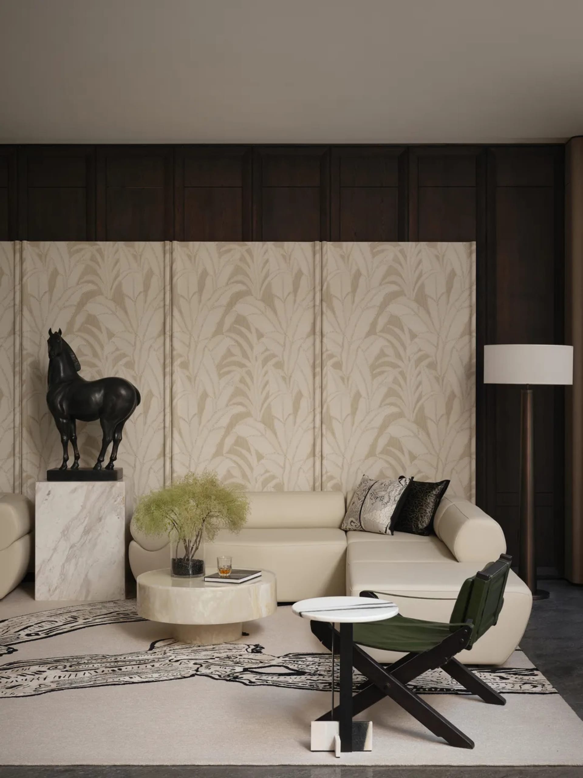 A modern living room featuring a white leather sofa, marble coffee table, and dark wood accents. A black horse sculpture stan