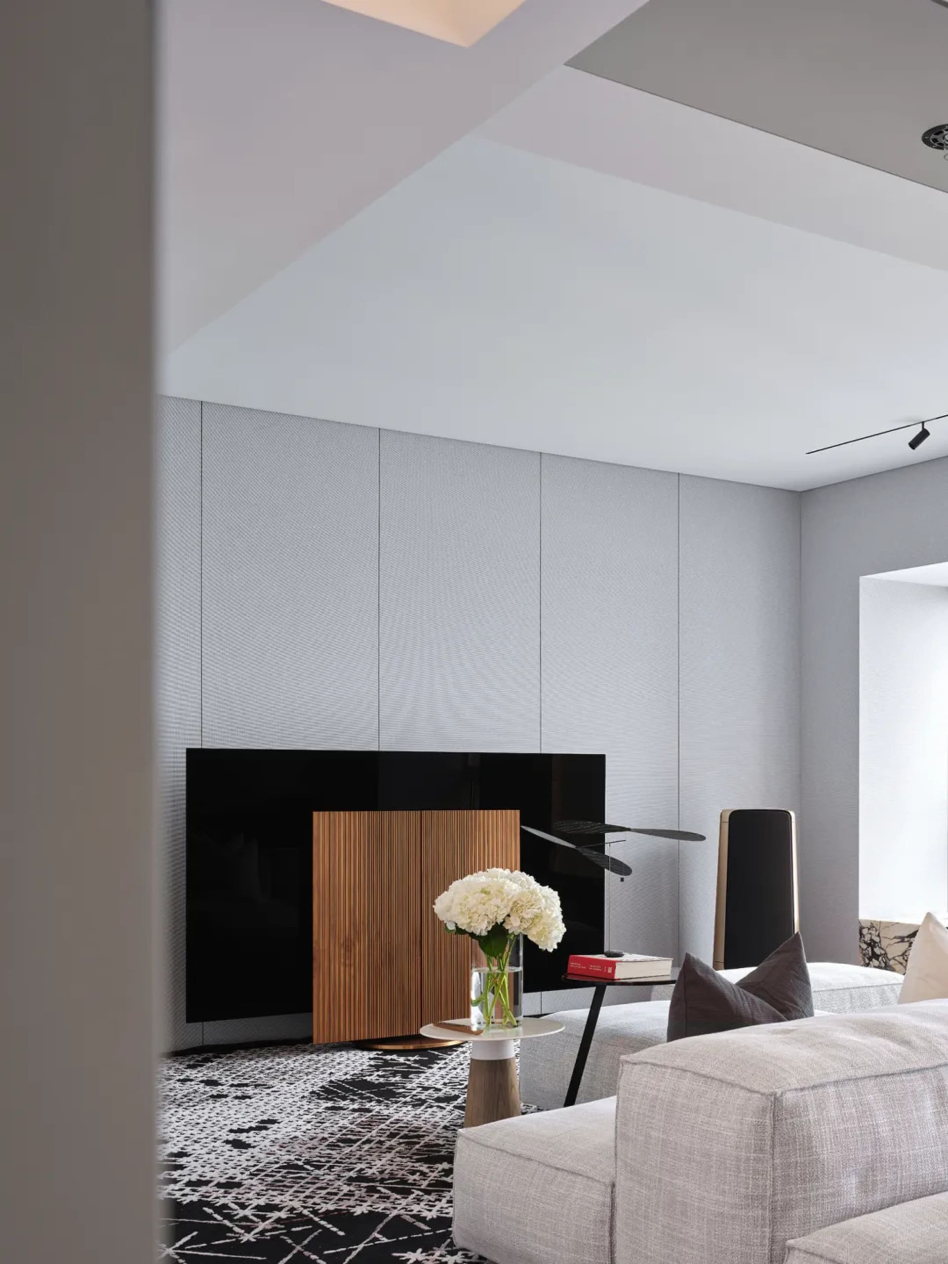 A modern living room featuring minimalist furniture, a wooden cabinet, and a gray sofa.