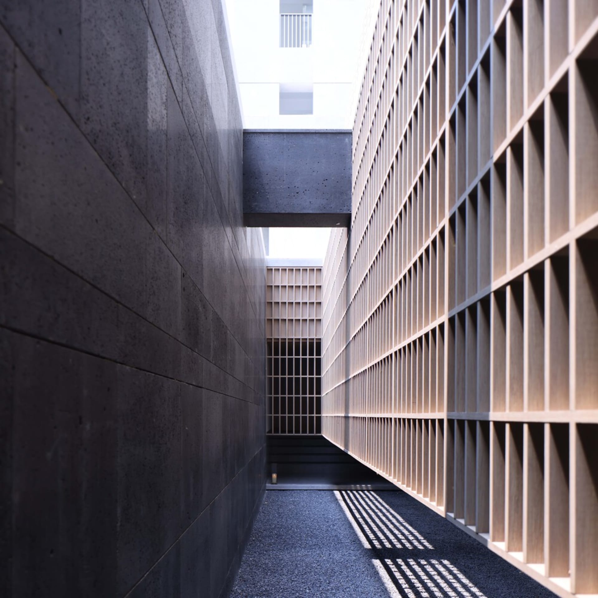 A modern lobby with concrete walls and a grid-like wooden panel system.