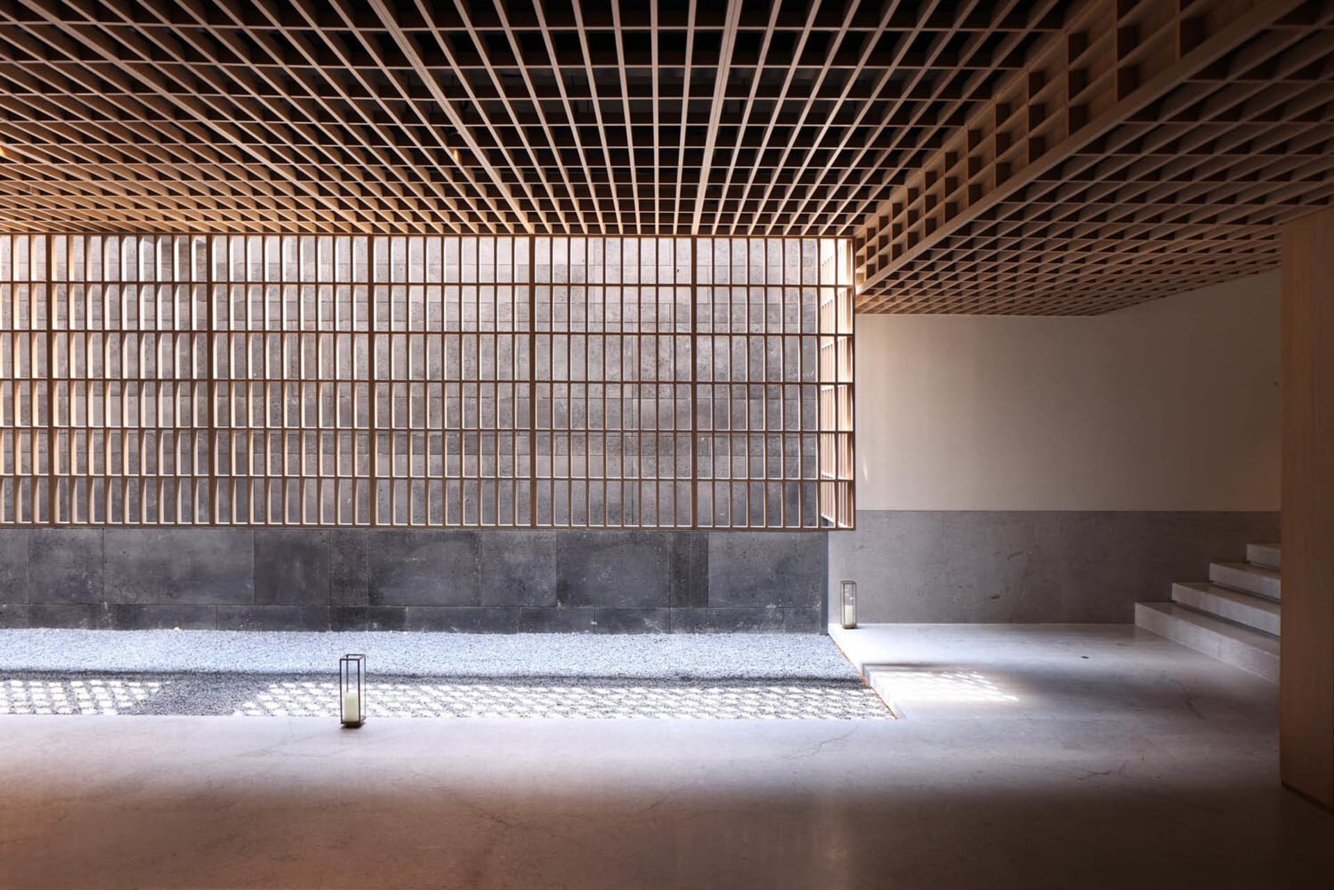 A minimalist interior design featuring wooden ceiling beams and concrete walls.