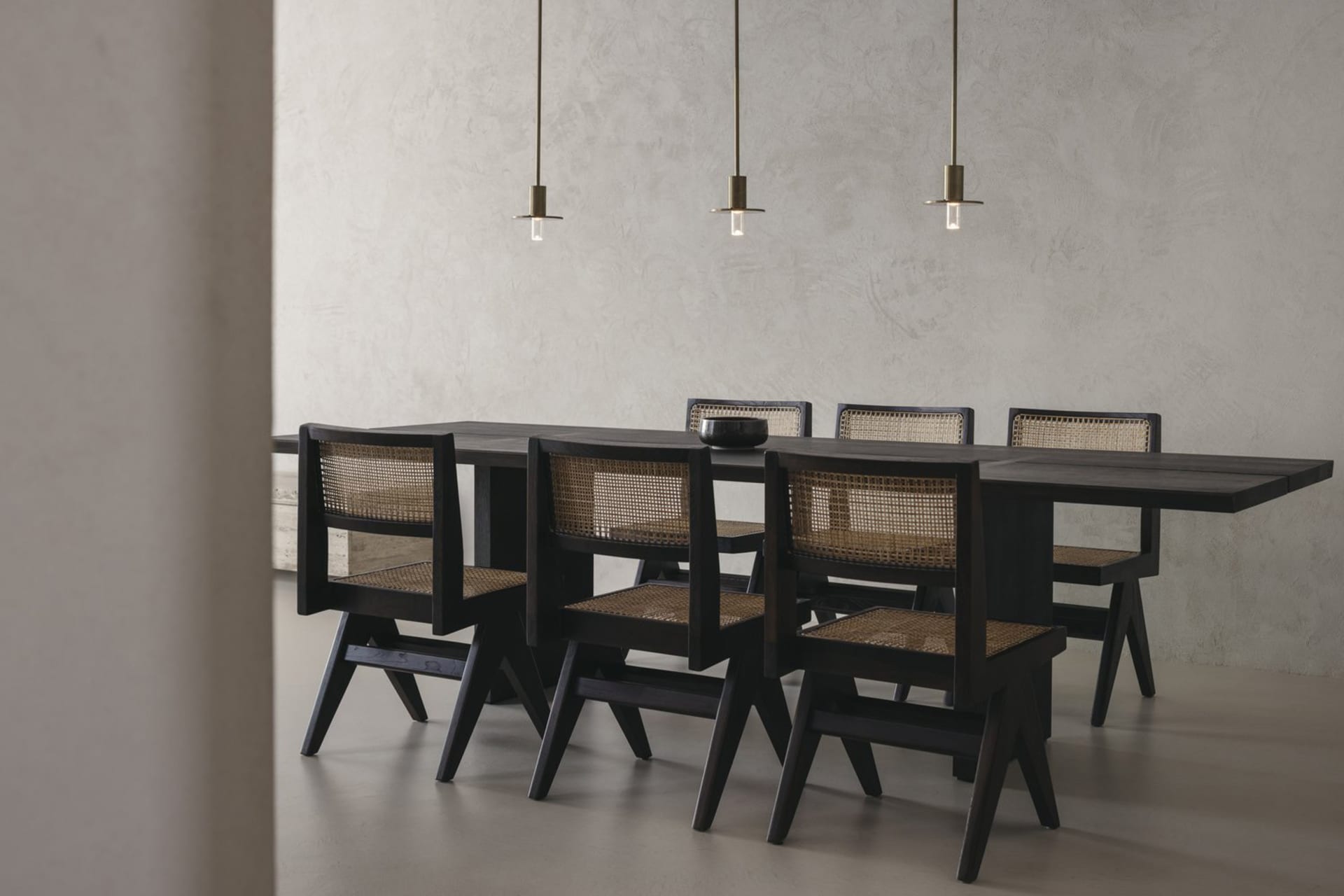 Modern industrial dining room with black and wood furniture, and hanging pendant lights.