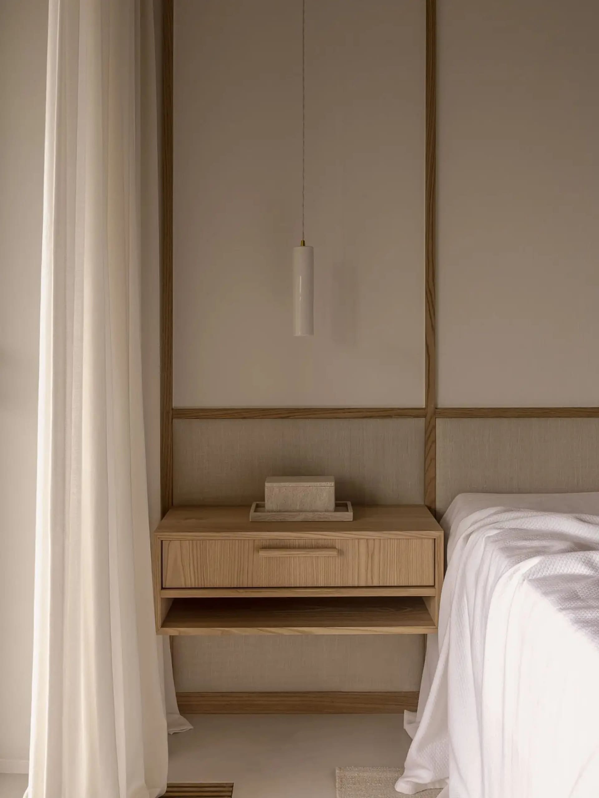 Minimalist bedroom with a floating nightstand, wooden elements, and a sleek pendant lamp.