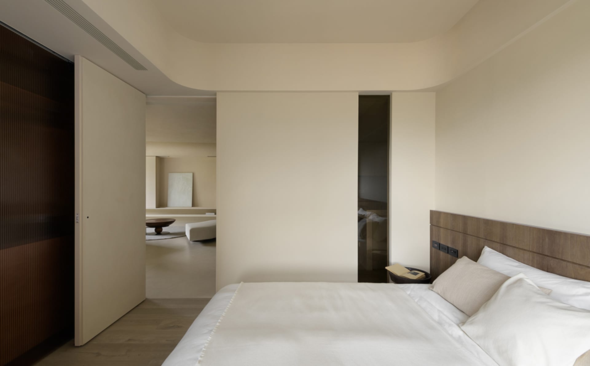 Bedroom with minimalist design featuring wooden walls and white bedding.
