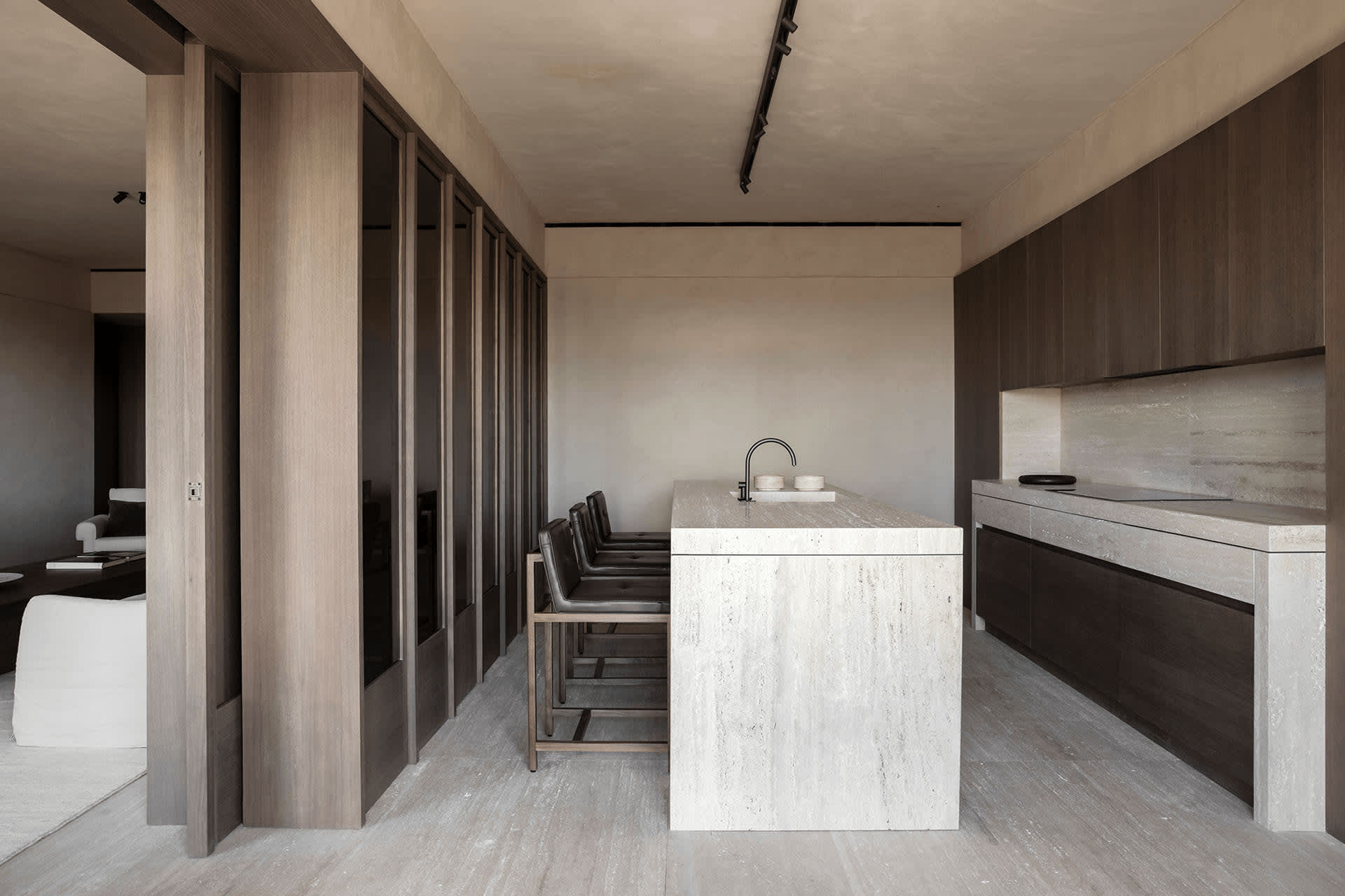 Minimalist residential kitchen with a concrete island counter and seating, featuring sleek, dark wood cabinetry and a polishe