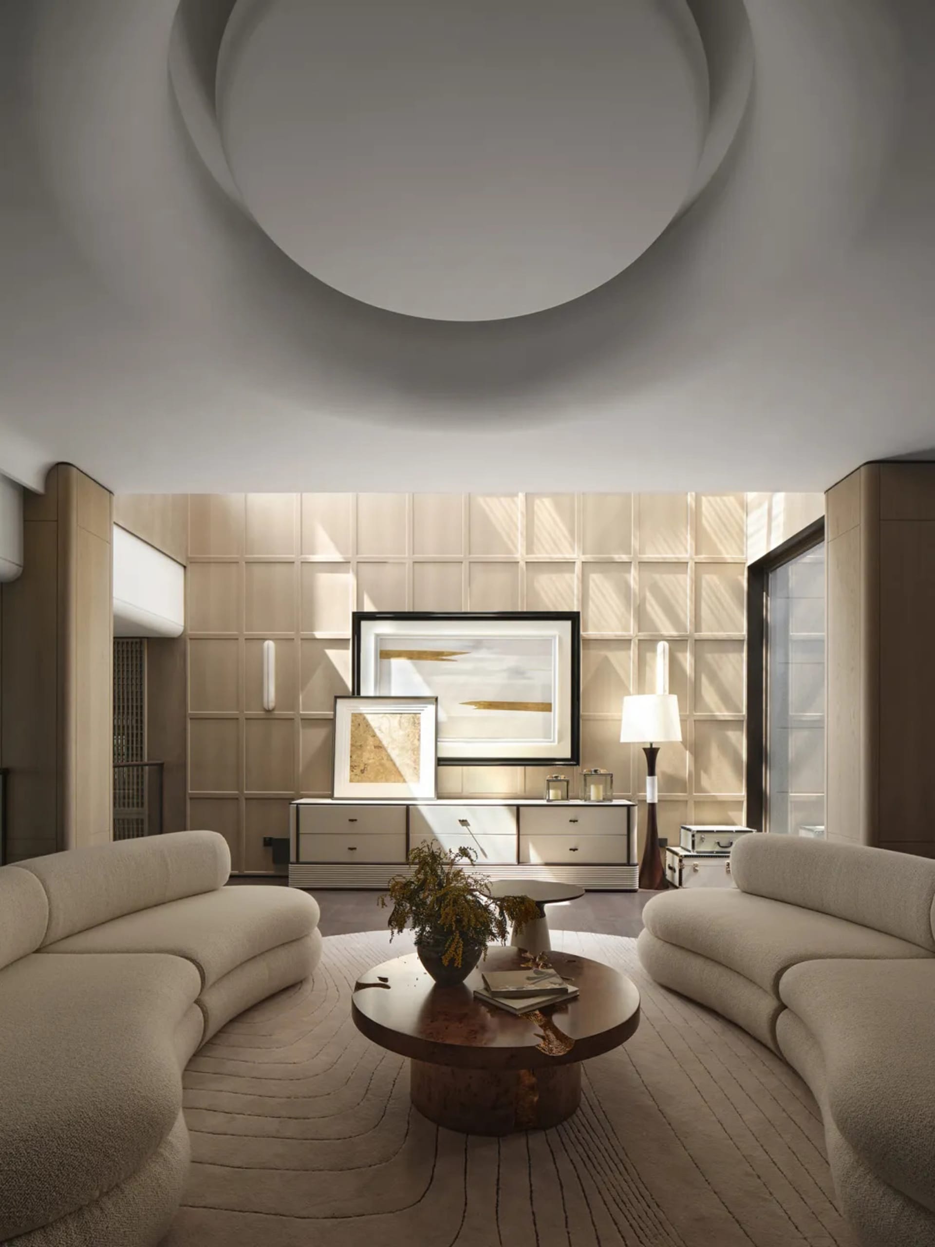 A modern interior living room with curved sofas, a round wooden coffee table, and a minimalist art gallery wall.