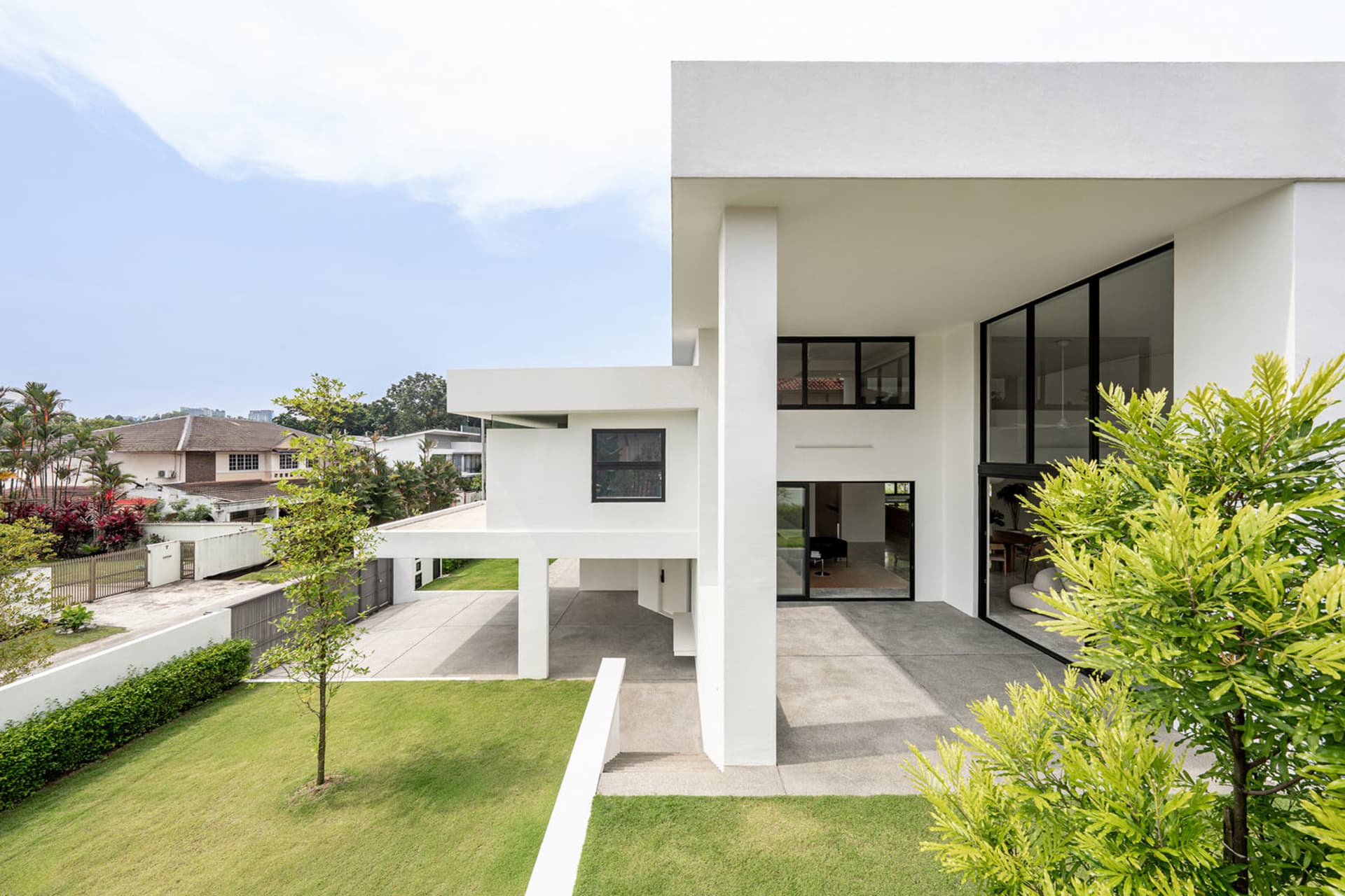 A modern, minimalist house with white walls and large glass windows.