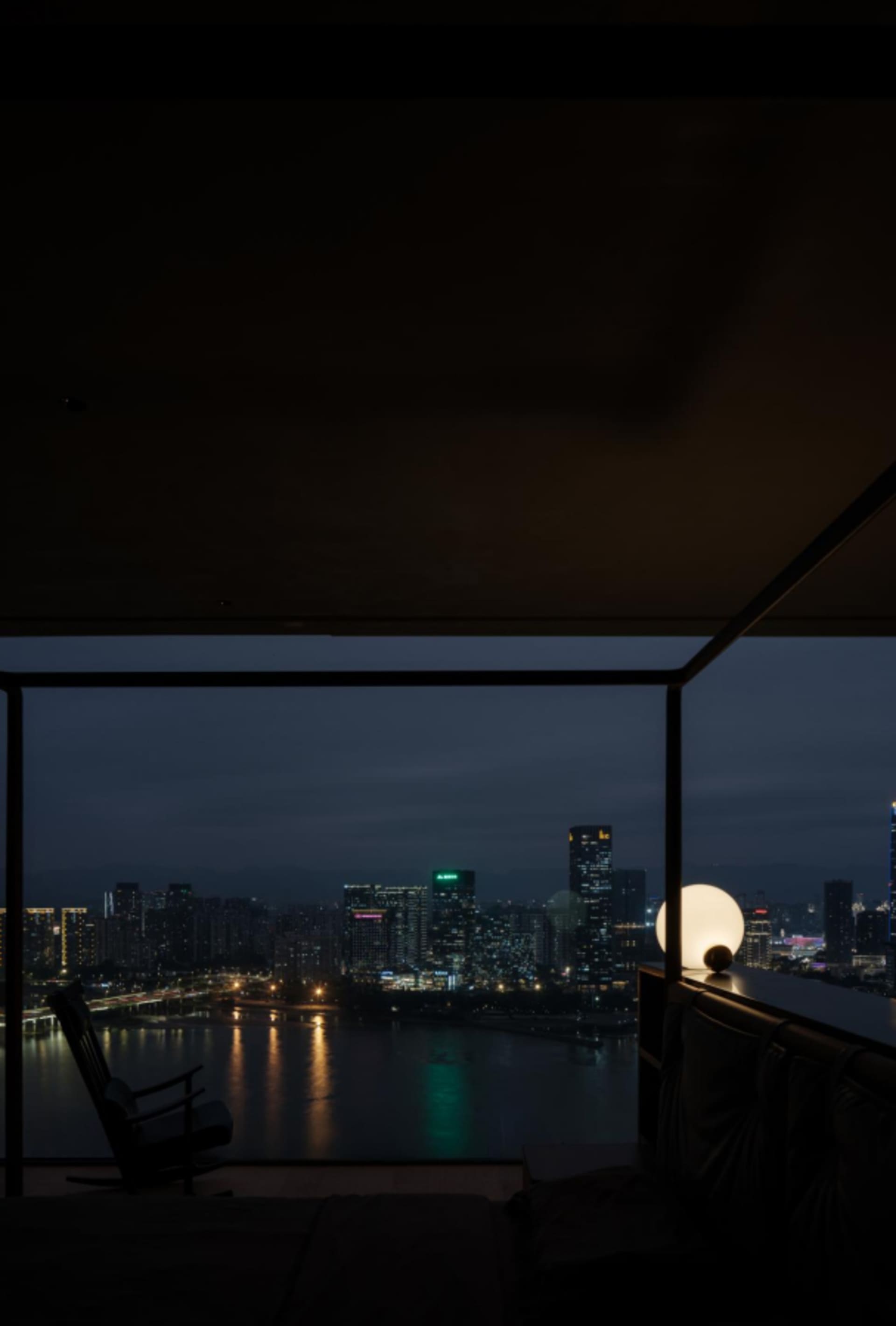 Interior night view showing a cityscape through a glass window frame.