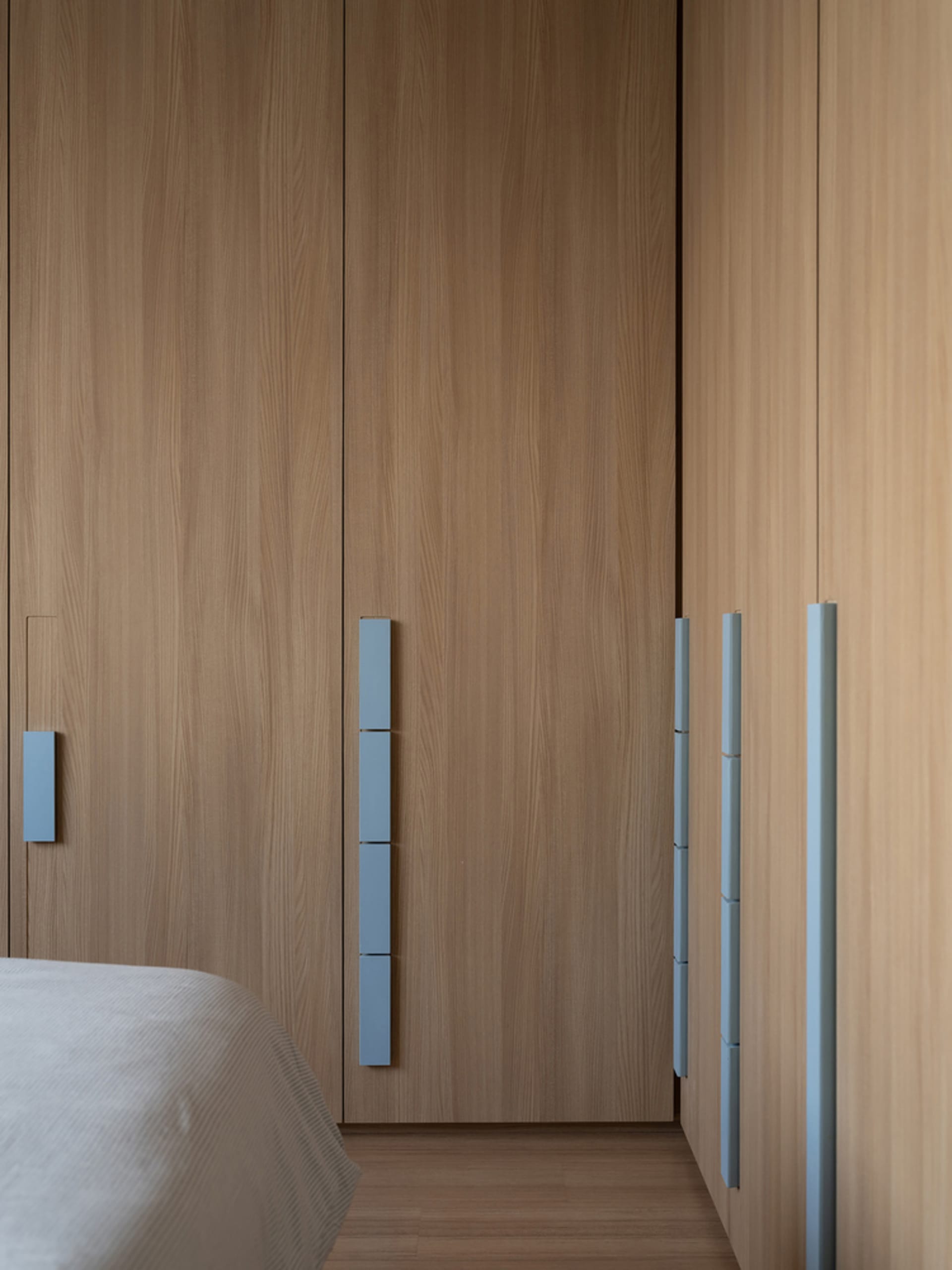 A modern minimalist bedroom featuring wooden furniture and paneling.