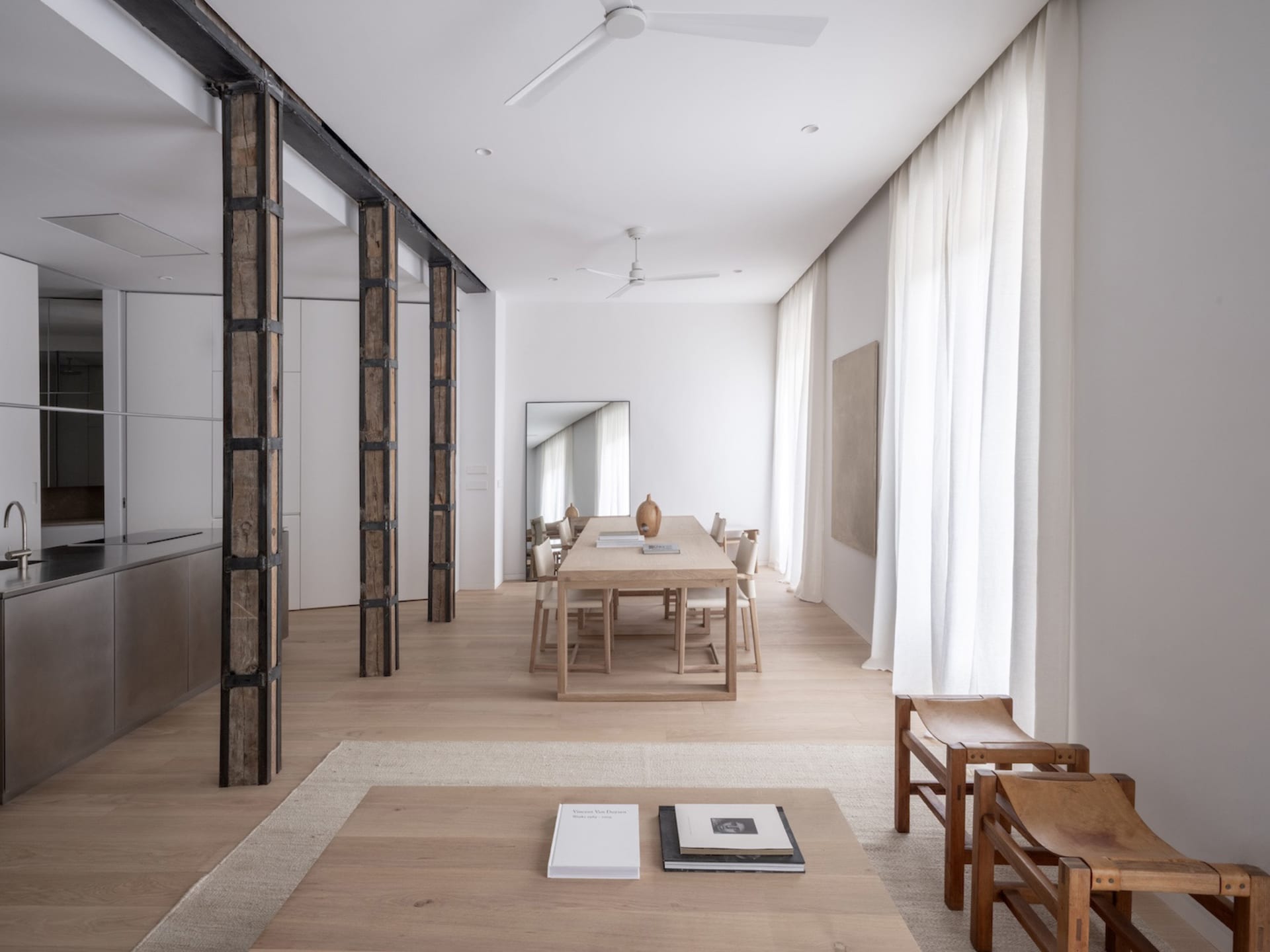 Modern minimalist living room with white walls, wooden furniture, and steel accents.