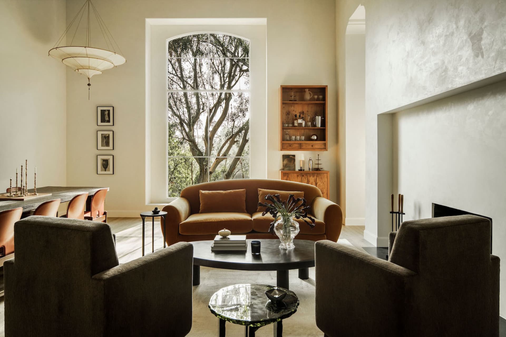 A modern living room with a velvet sofa and wooden cabinet against a wall with a large window.