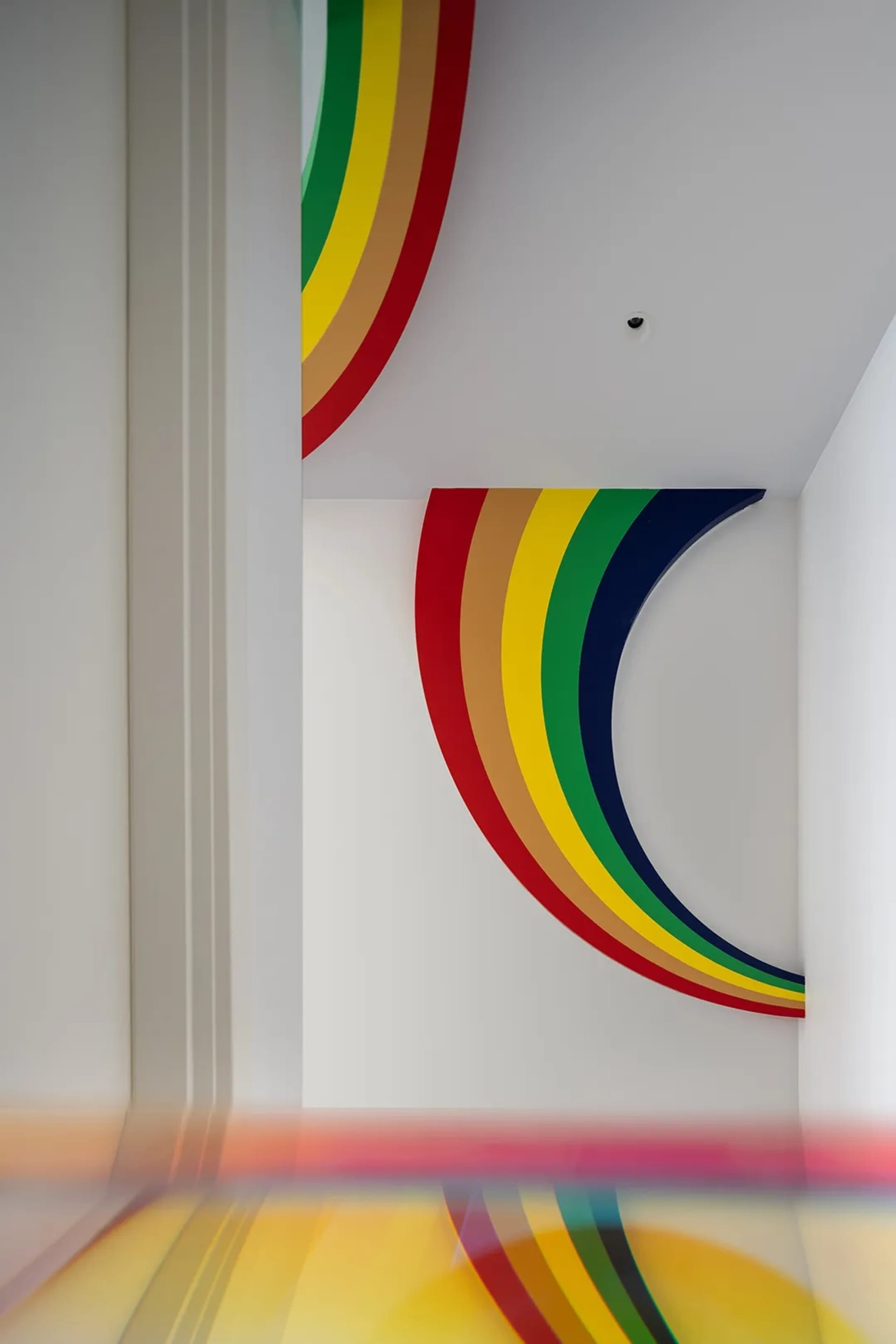 A vibrant, colorful wall decoration composed of overlapping arcs in red, yellow, green, and blue.