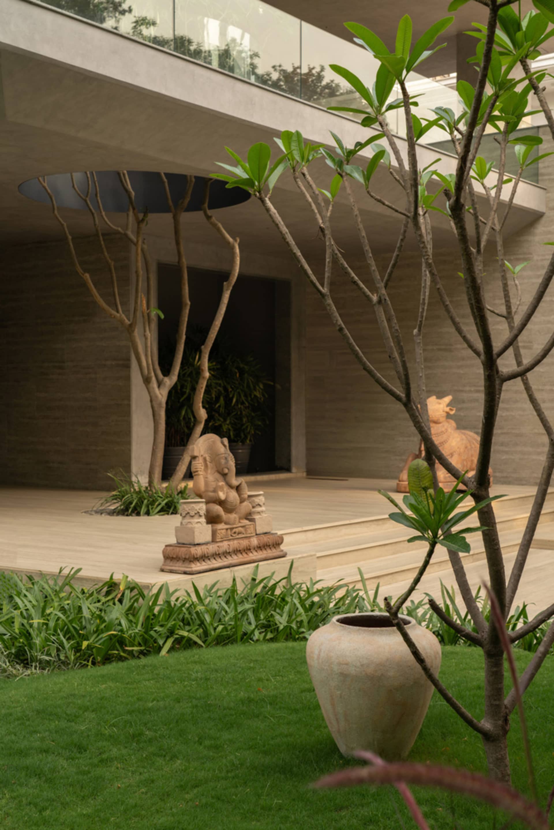 A serene garden landscape featuring a concrete patio, stone sculptures, and lush greenery.