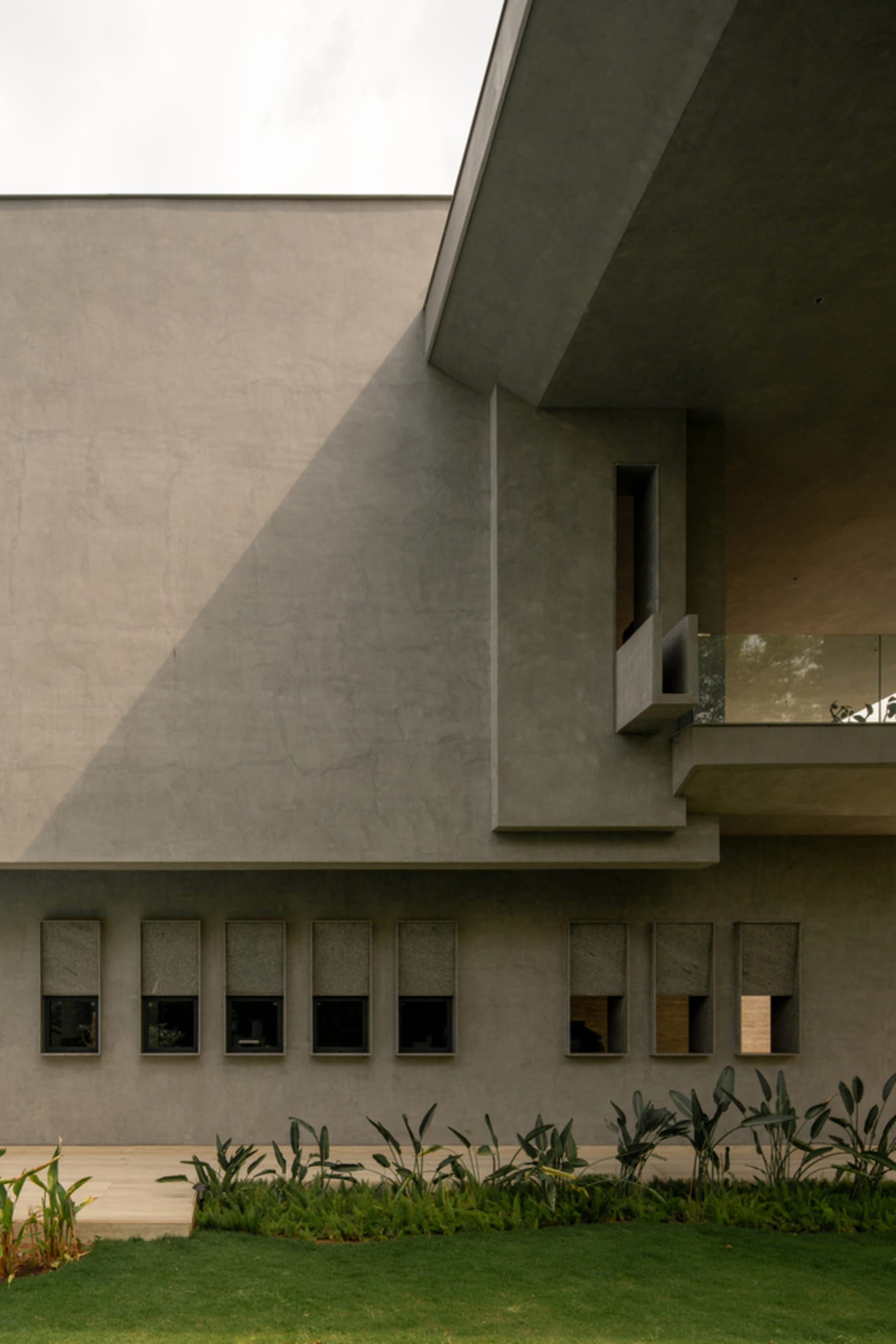 A modern house with a concrete exterior and landscaped garden.