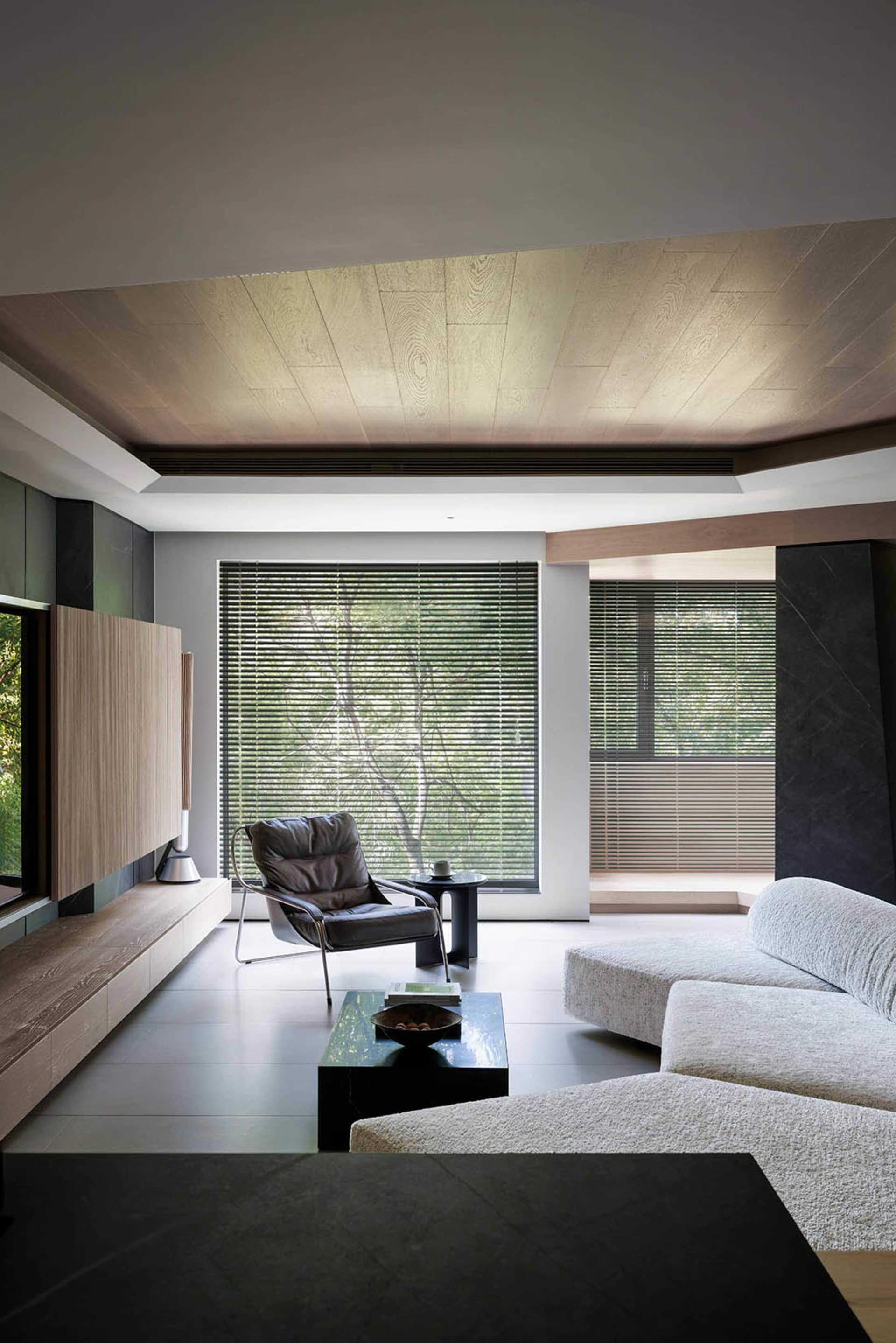 A modern living room with glass walls, a wooden floor, and a sofa.
