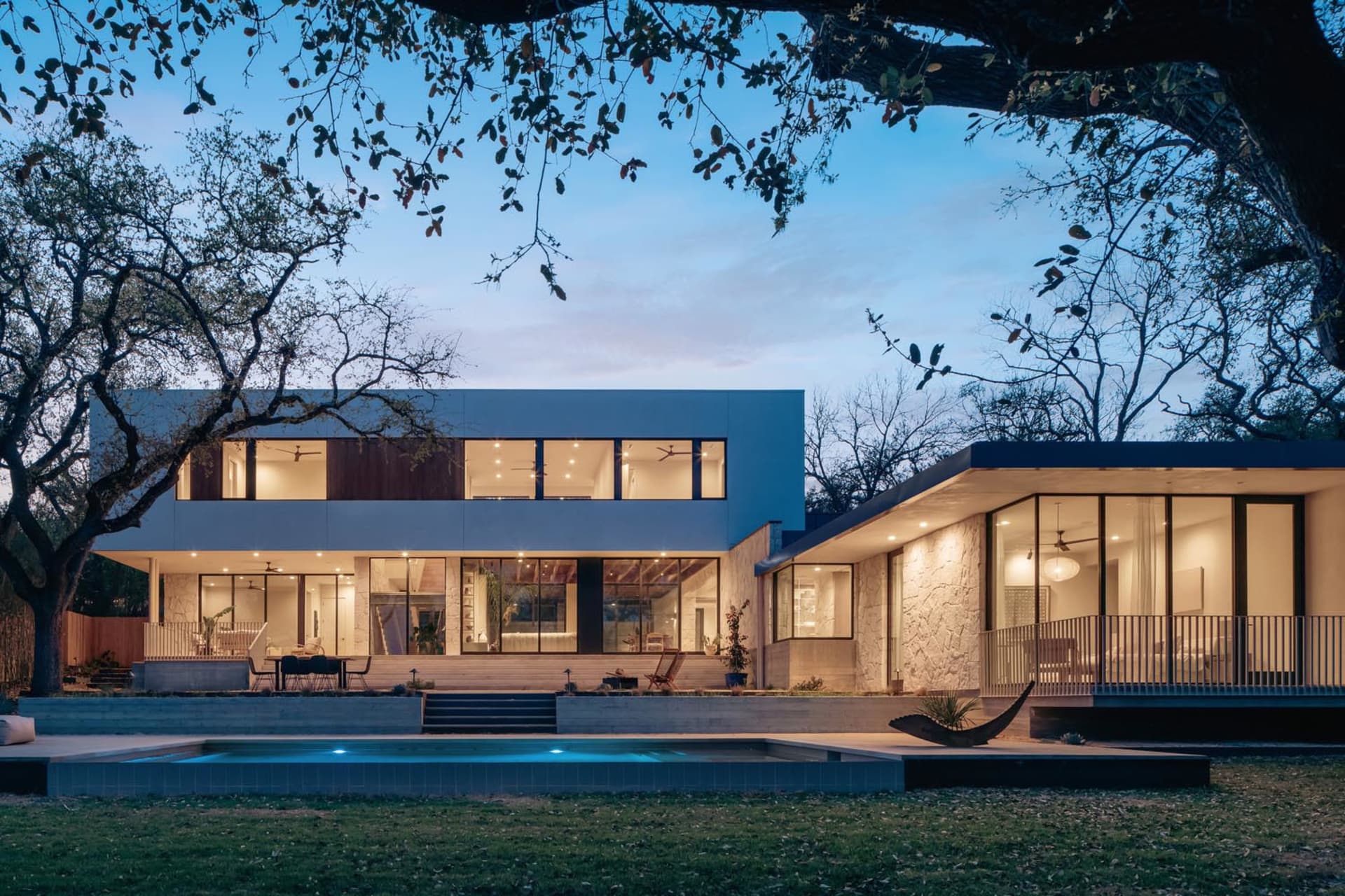 A modern residential exterior with a concrete finish and large windows.