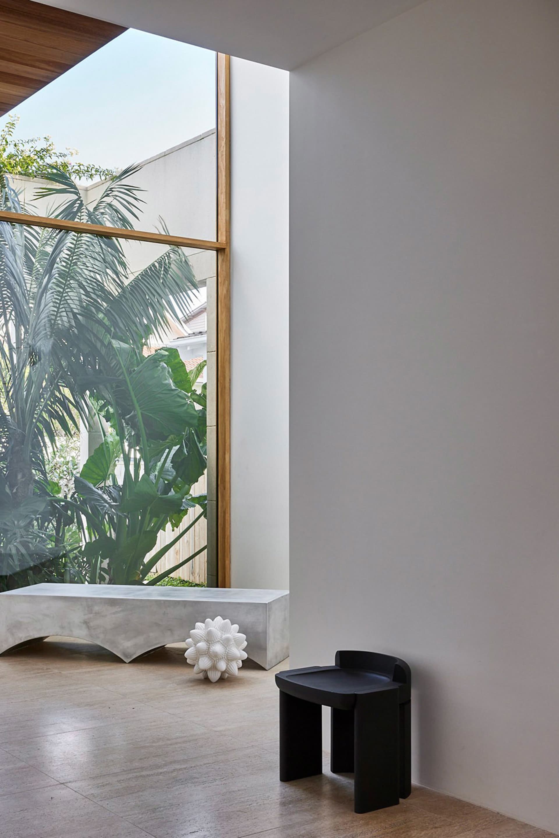 Minimalist architectural space with concrete window and garden view, showcasing industrial and natural elements.