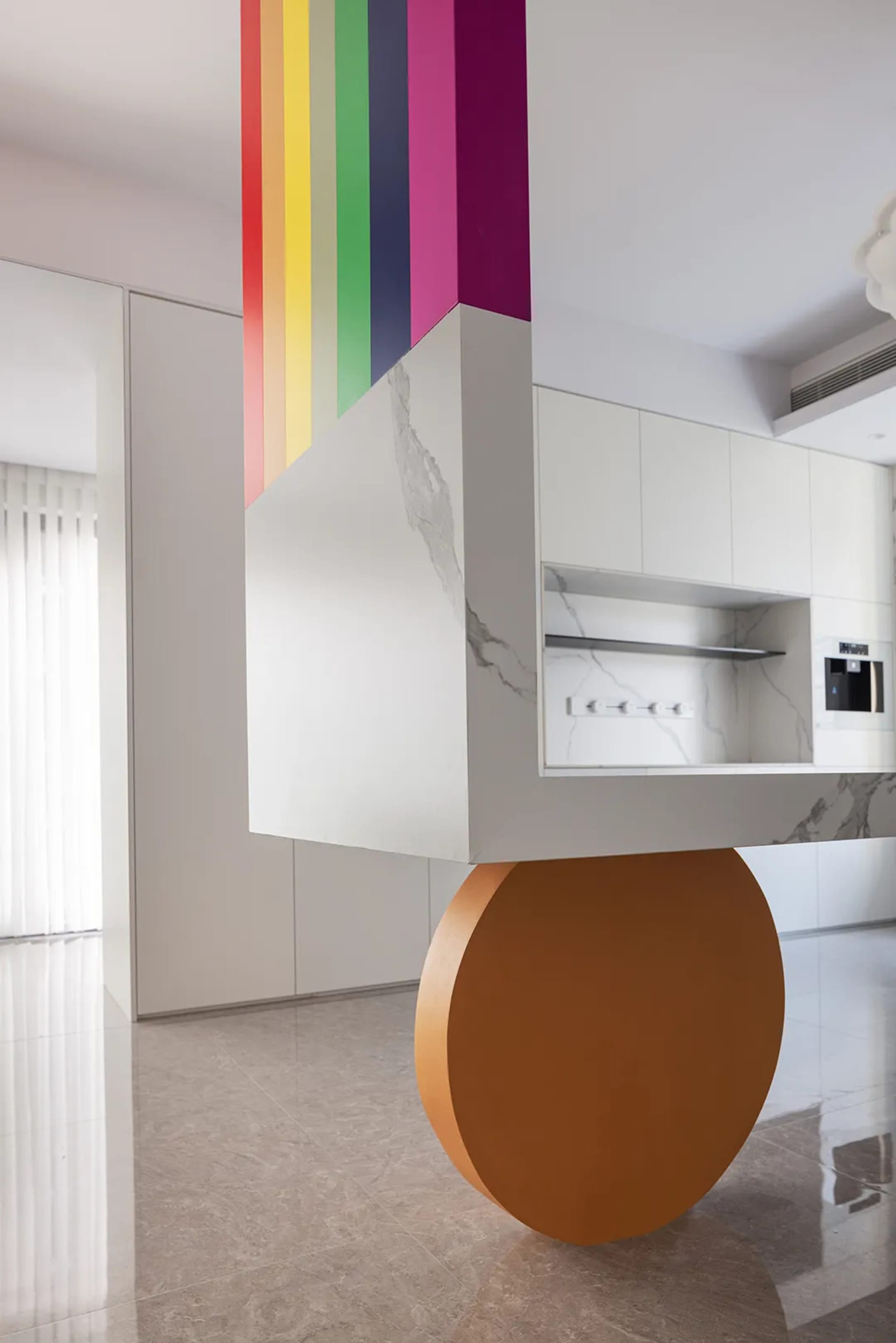 A modern, open-concept kitchen with colorful stripes on the wall and a floating island counter.