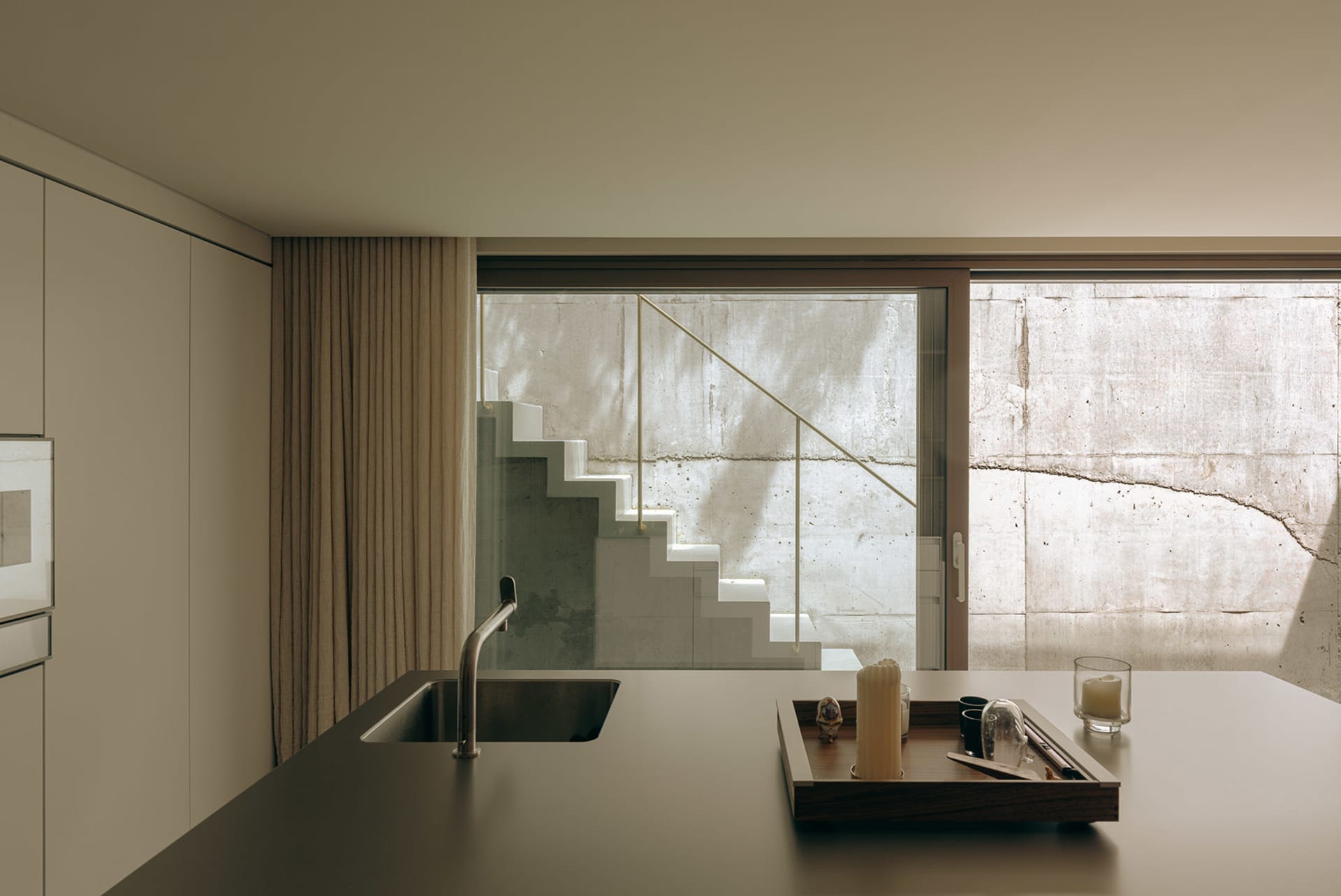 A modern, minimalist residential kitchen featuring concrete elements.