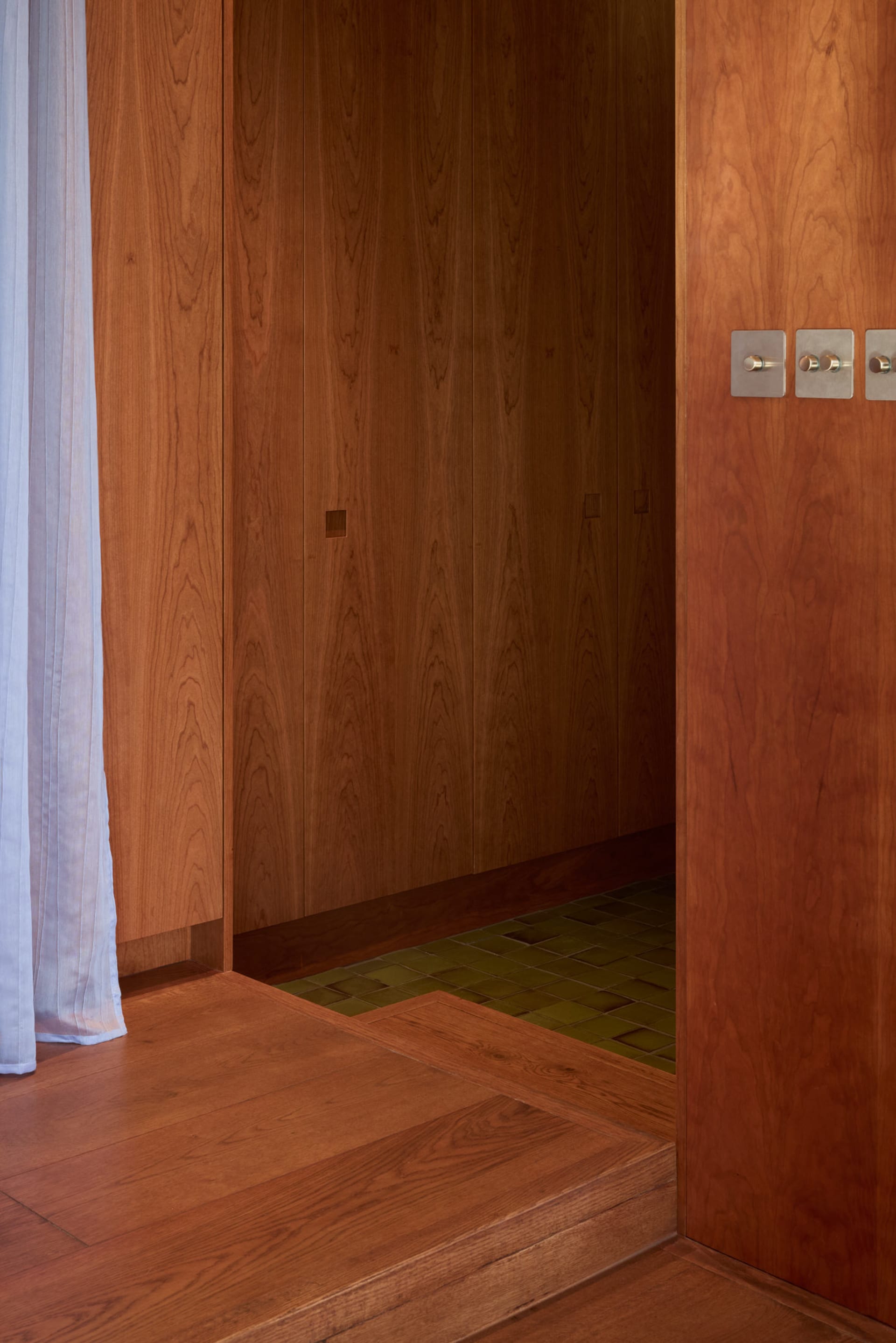 Modern closet interior with wooden walls, tiled flooring, and metal light switches.