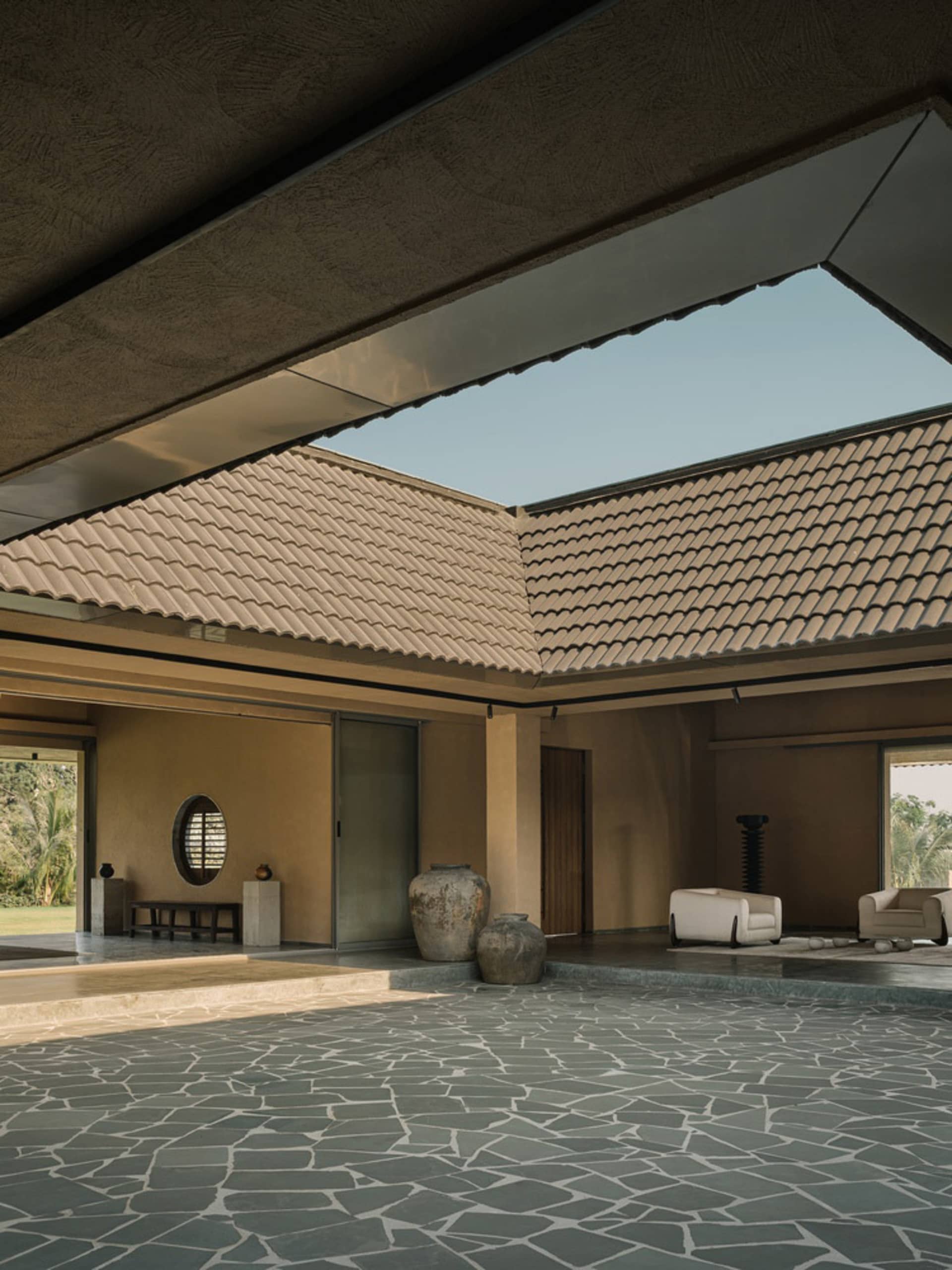 A modern living room with concrete walls, a stone floor, and a skylight.