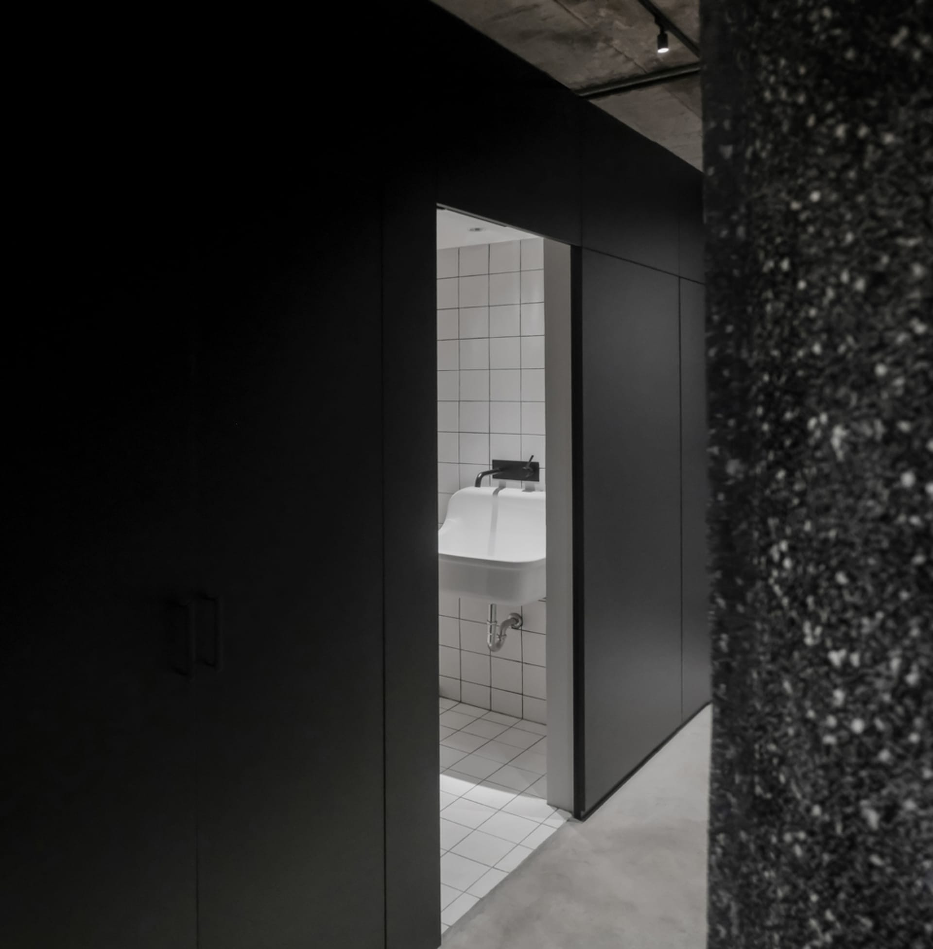 Bathroom with industrial design featuring concrete flooring and white tiled walls