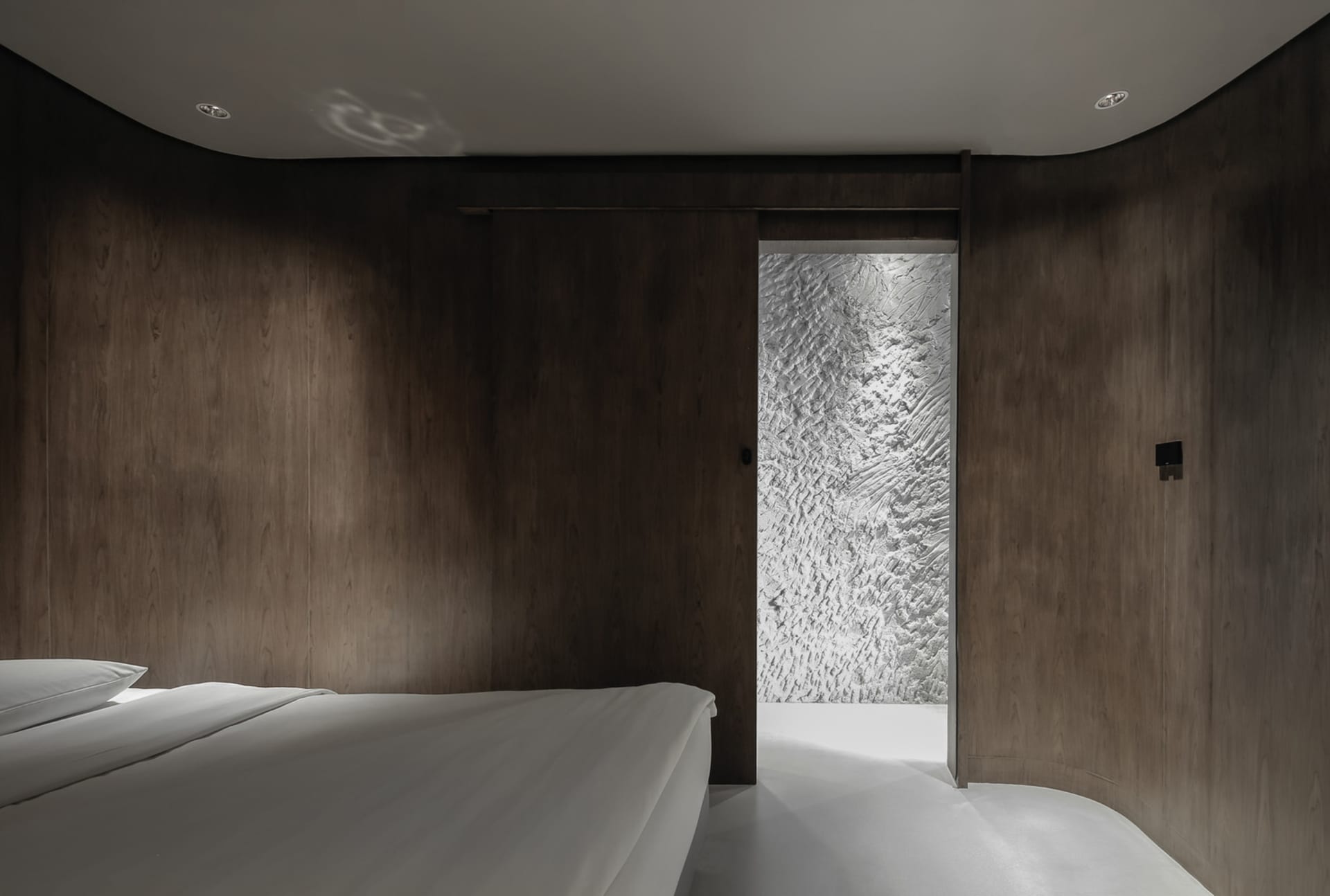 Minimalist bedroom with white bedspread and wooden panel walls