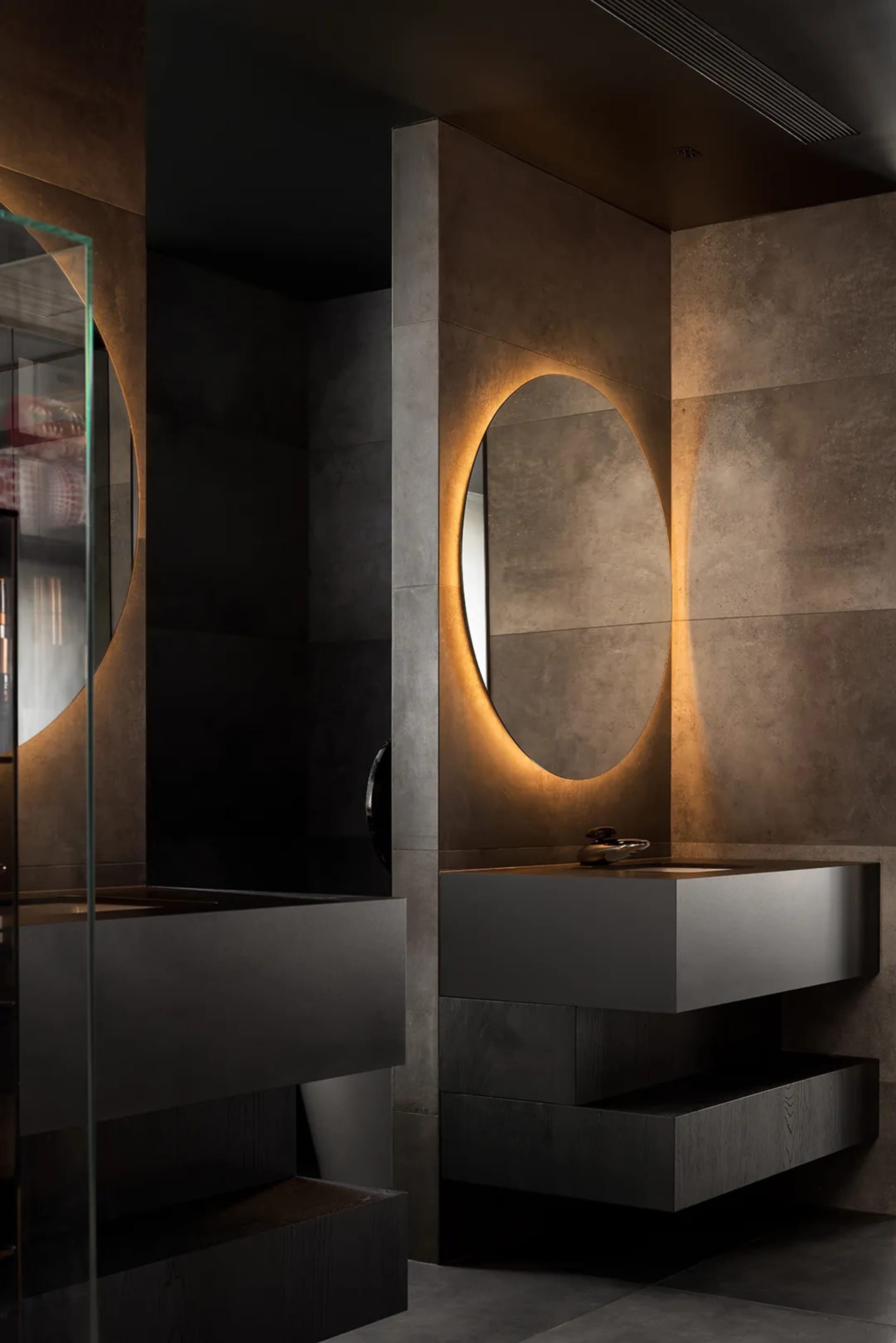 A modern bathroom featuring concrete walls, metal fixtures, and glass elements.