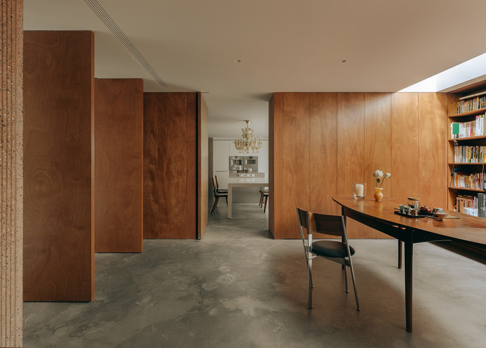 A modern dining room with wooden walls, a wooden dining table, and a concrete floor.