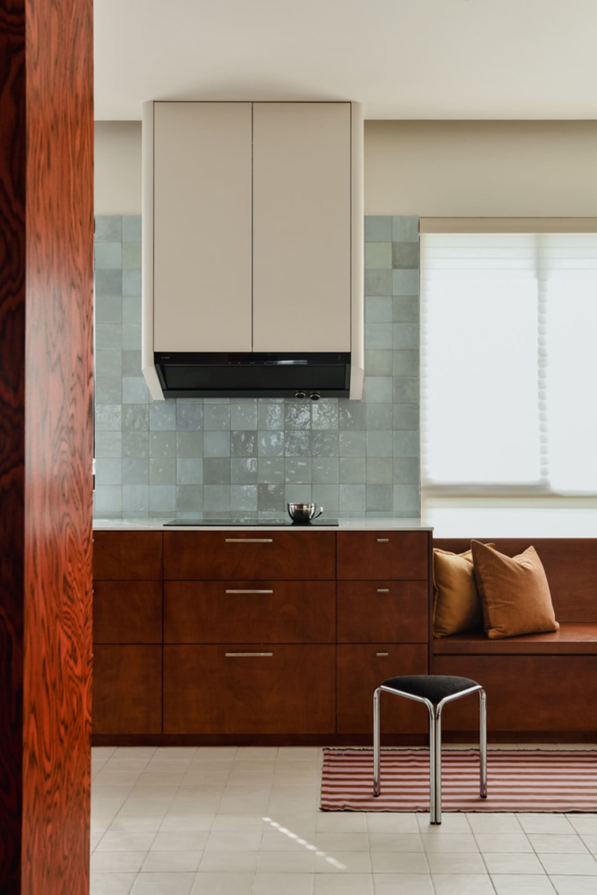 A modern kitchen with white cabinets, wooden drawers, and a tiled backsplash.