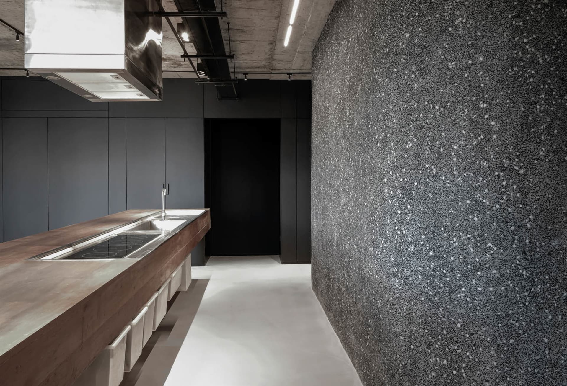 Modern minimalist kitchen with concrete countertop, featuring sleek, clean lines and a monochromatic color palette.