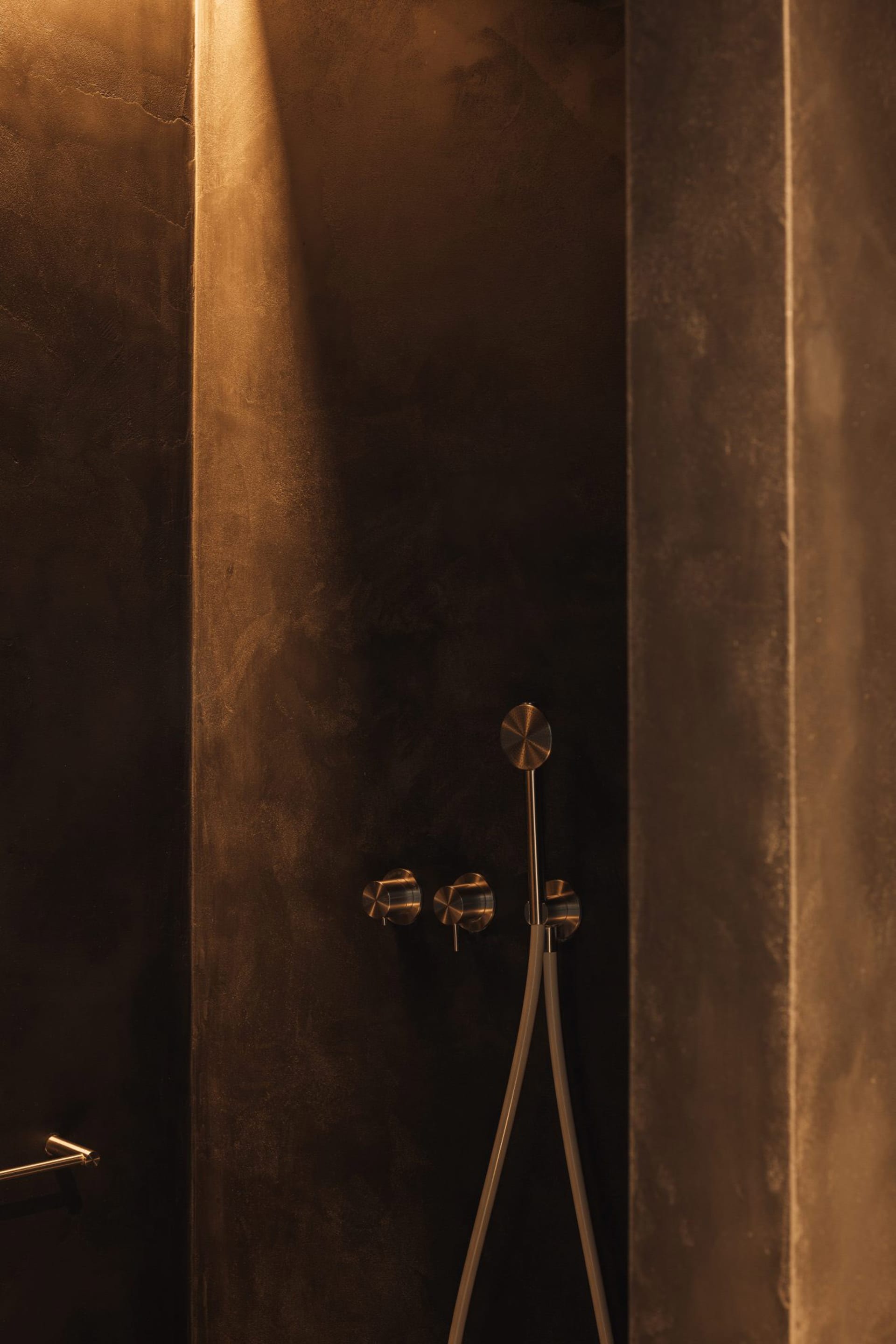 Concrete shower area with metallic fixtures in a modern bathroom interior