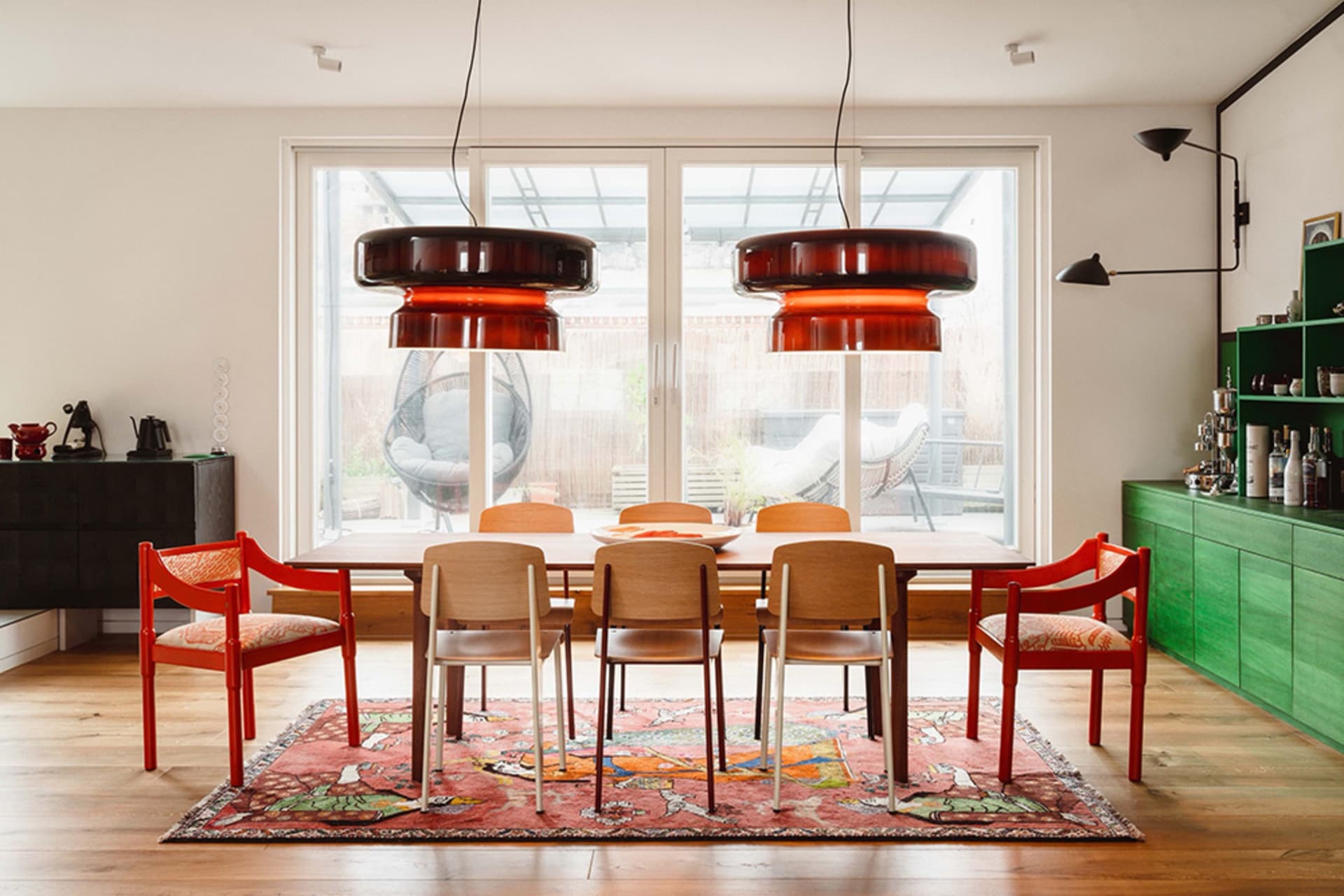 Dining room with modern furniture, wooden table, leather chairs, and ceramic pendant lights.