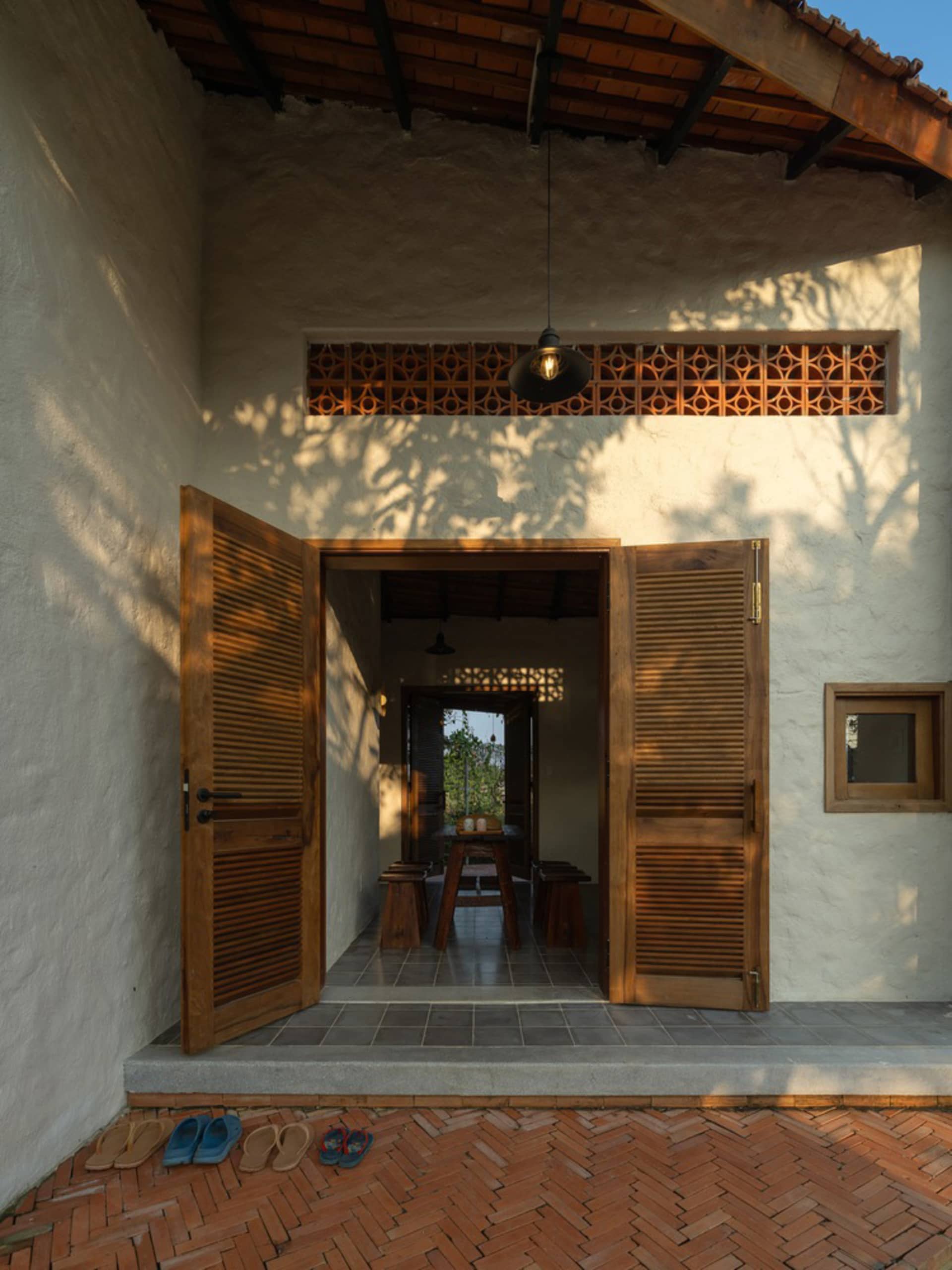 A rustic house entryway featuring wooden doors, a concrete wall, and tiled flooring.
