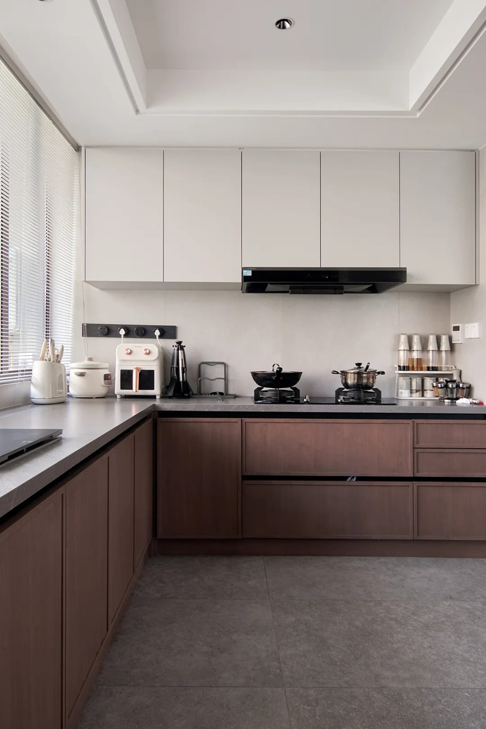 Modern industrial kitchen with wooden cabinets and grey countertops.