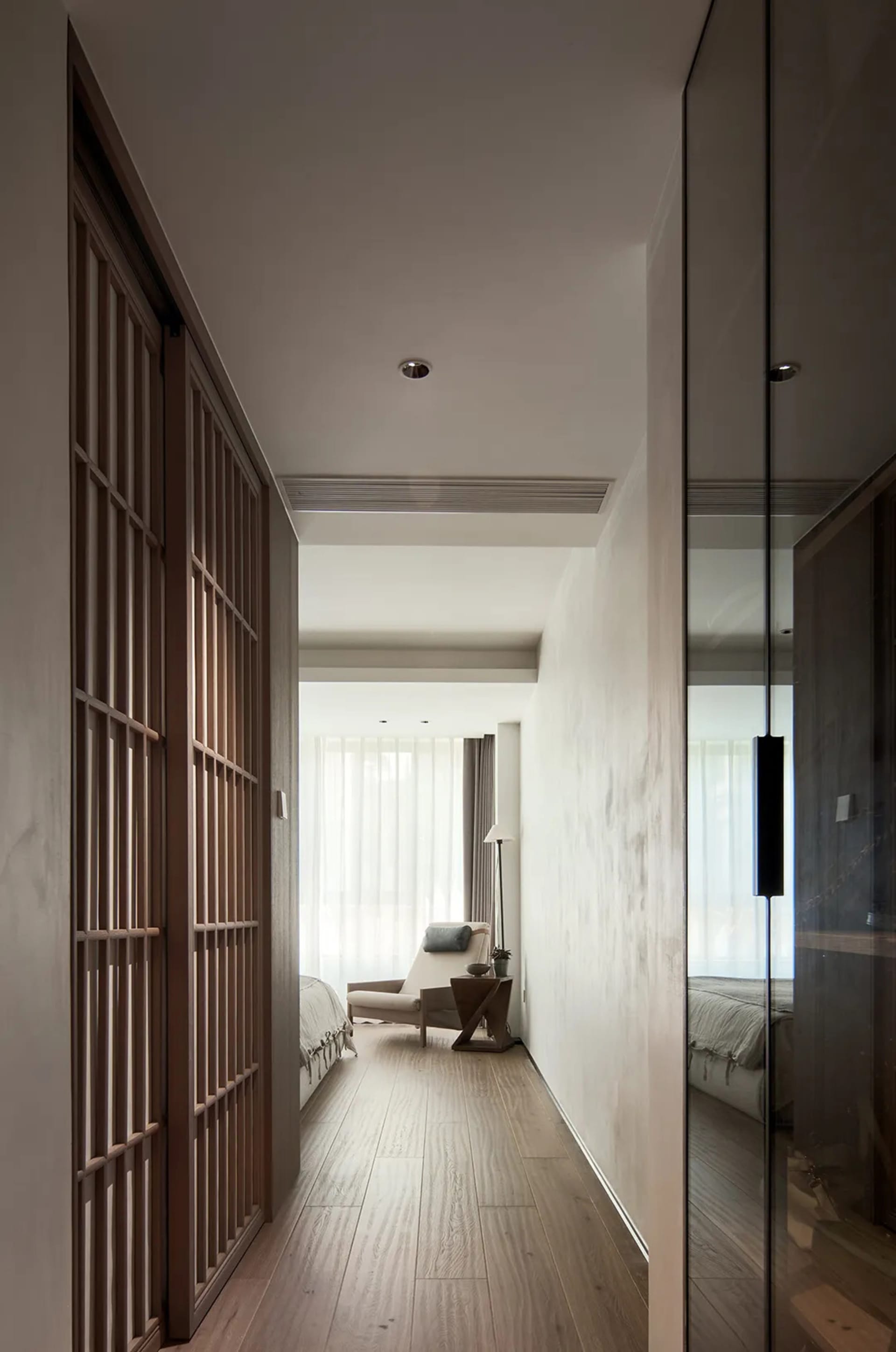 Modern minimalist bedroom featuring a glass window and furniture with neutral tones