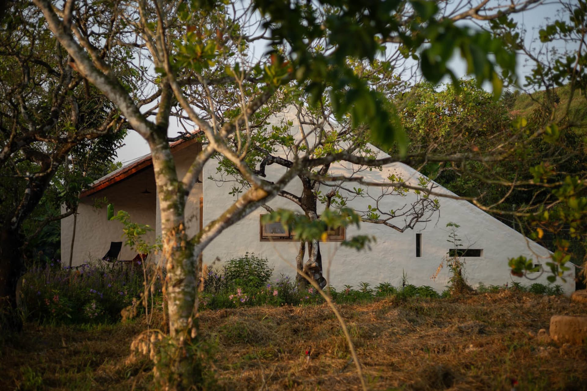 A traditional residential building with a white stucco exterior and wooden roof.