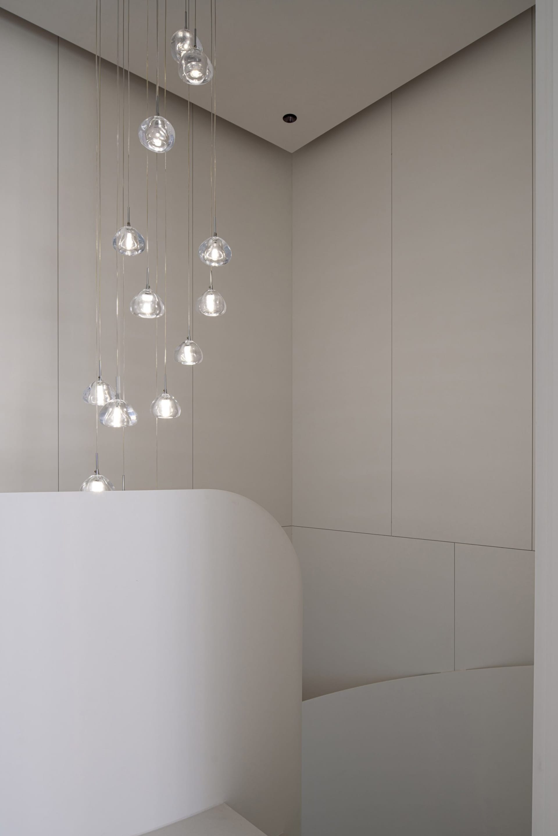 Minimalist bathroom with hanging glass light fixtures and curved white structure
