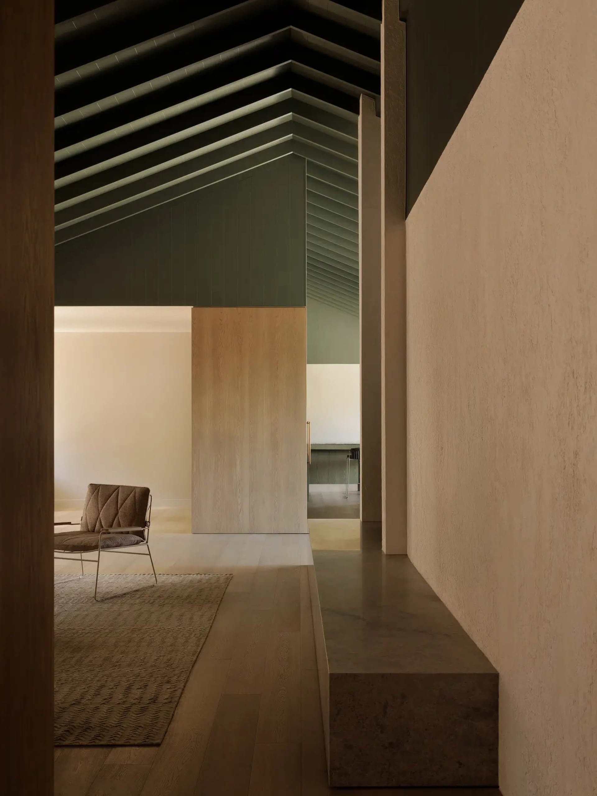 A modern residential living room with concrete flooring, minimalist decor, and a ceiling with exposed beams.
