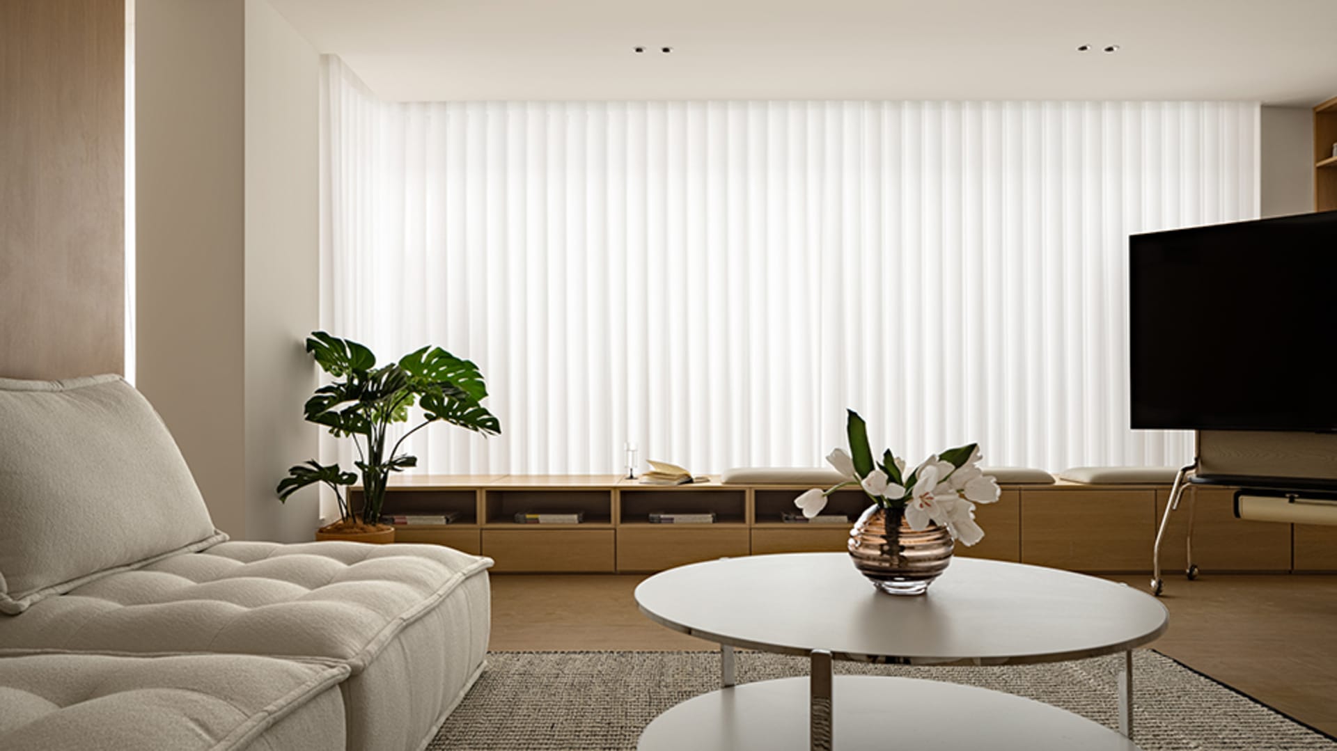 A modern living room featuring a cozy chair, green plant, and sleek coffee table in front of a large horizontal window with b