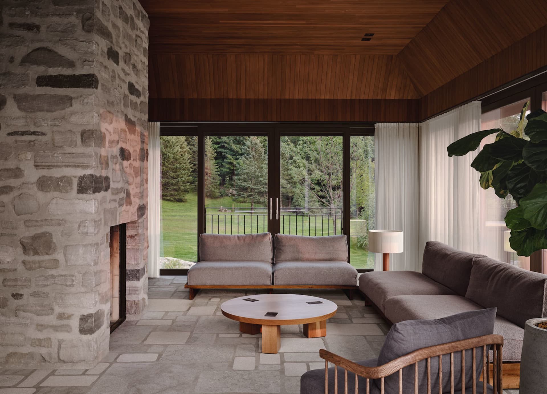 A cozy, modern living room with stone walls, a wooden ceiling, and comfortable furniture.