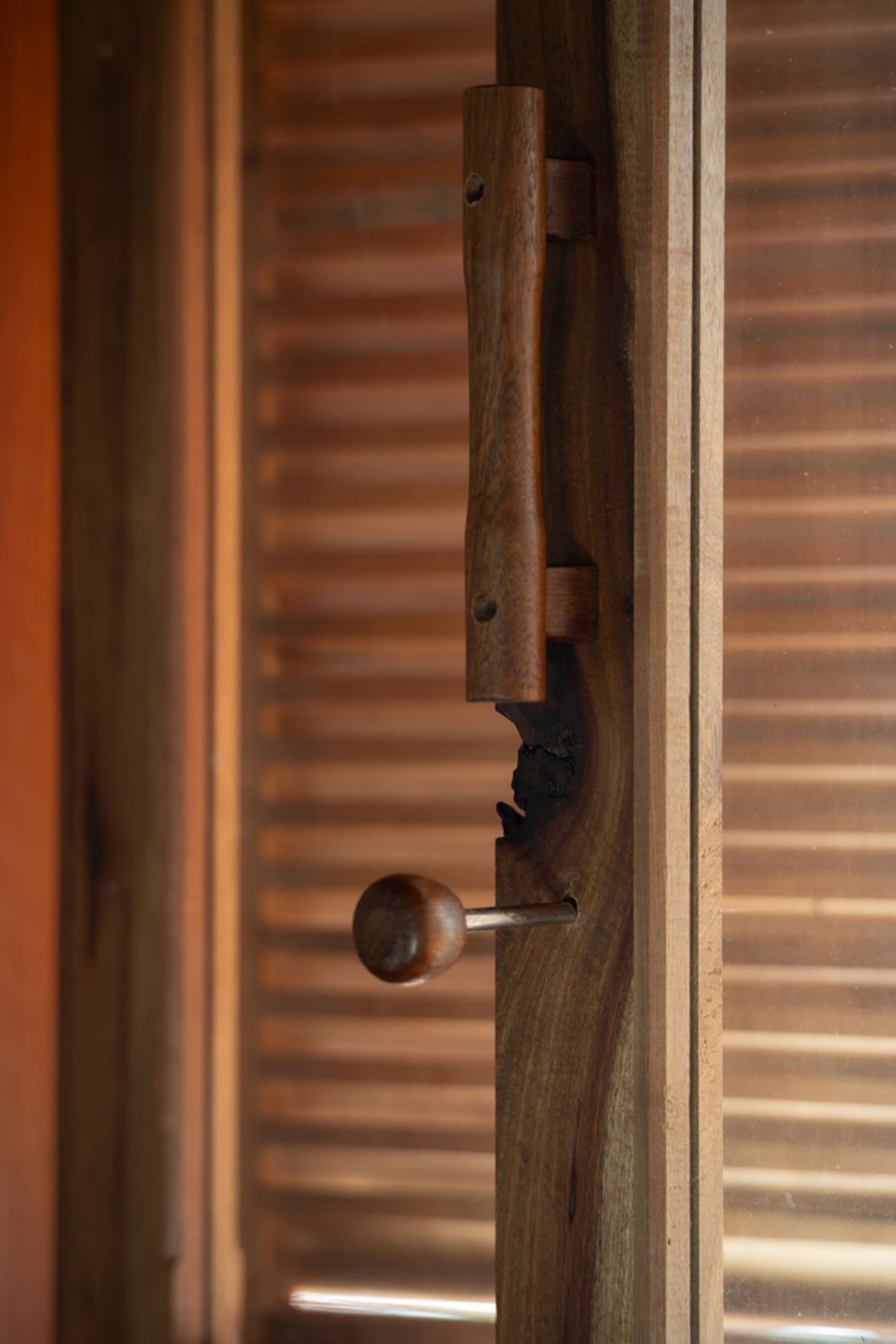 A close-up view of a wooden door handle and latch mechanism on a wooden door, highlighting the craftsmanship and texture of t